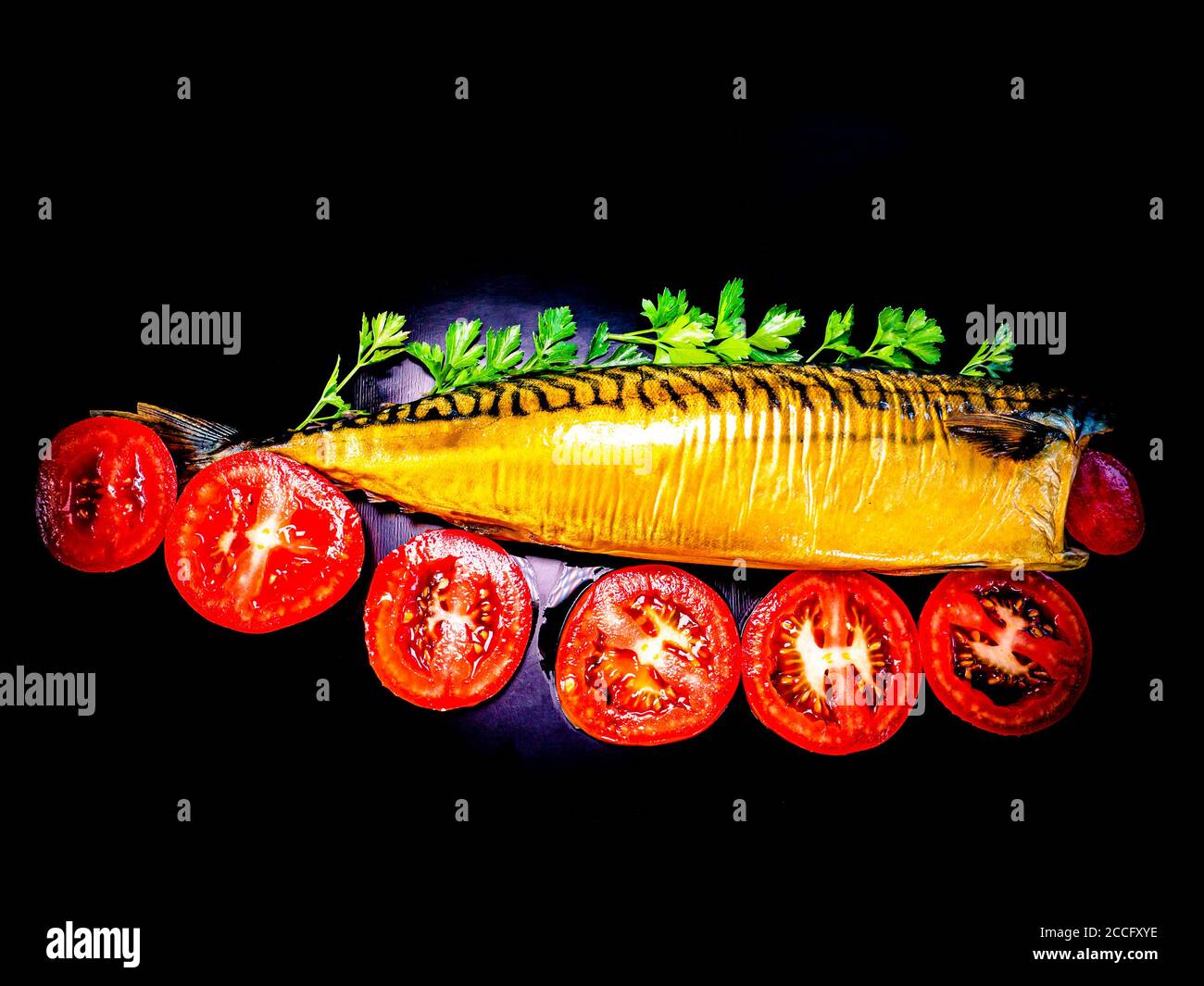 Smoked mackerel fish with tomatoes on a black background. Stock Photo