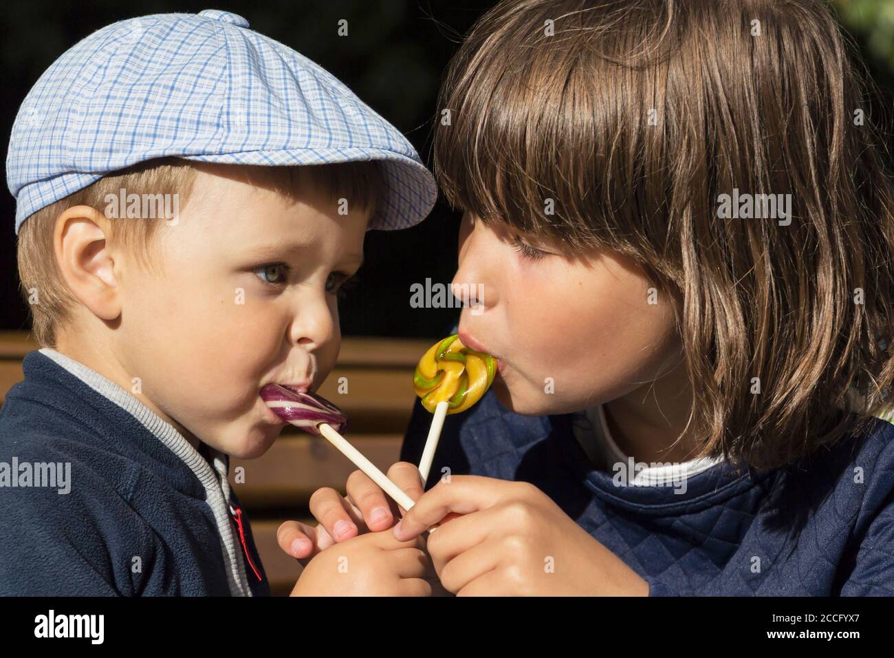 Boy and girl eating a delicious Lollipop.Cute boy licking Lollipop. Stock Photo