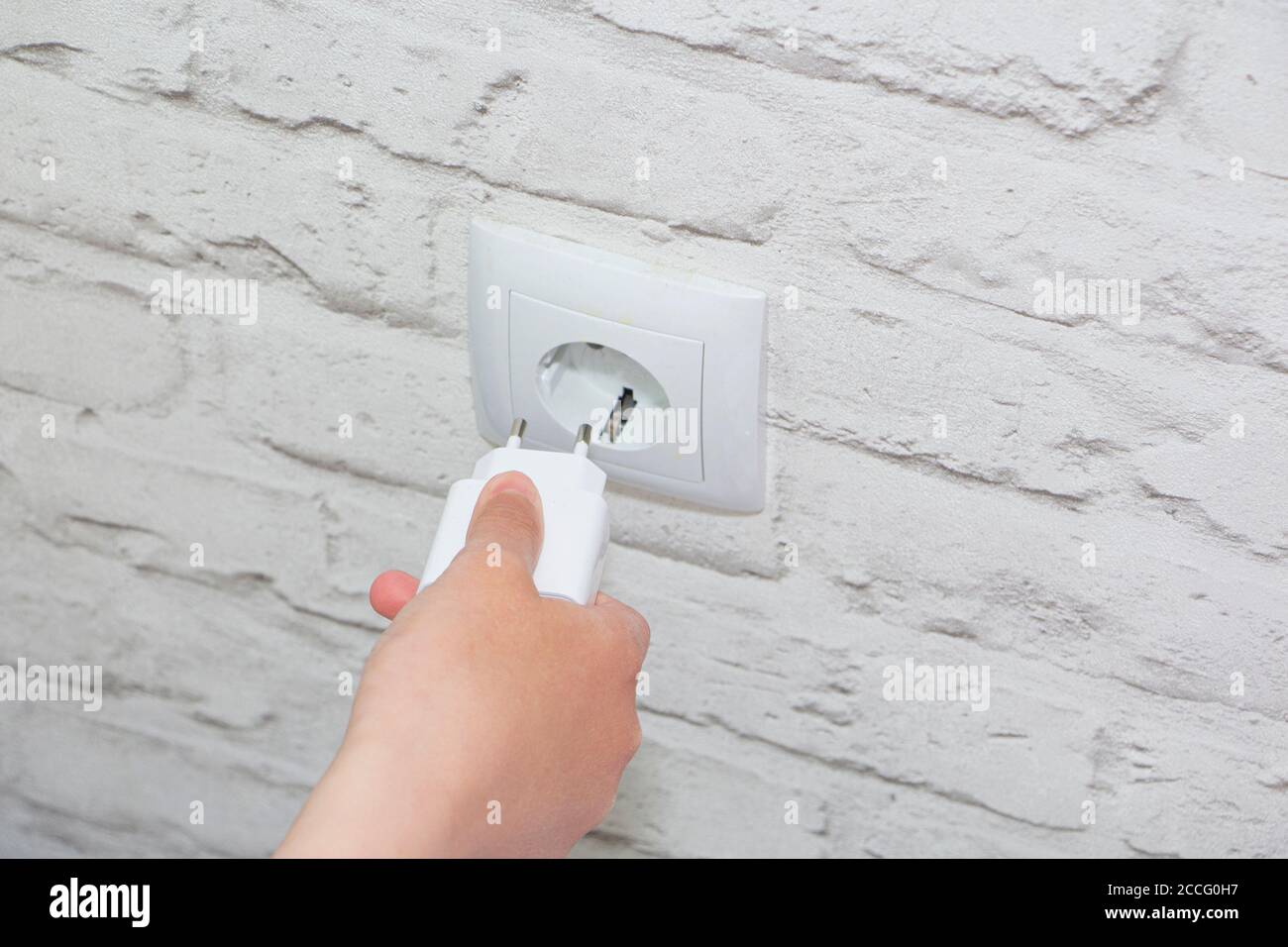 connect the charger to a wall outlet. Save energy-unplug the charger. Stock Photo