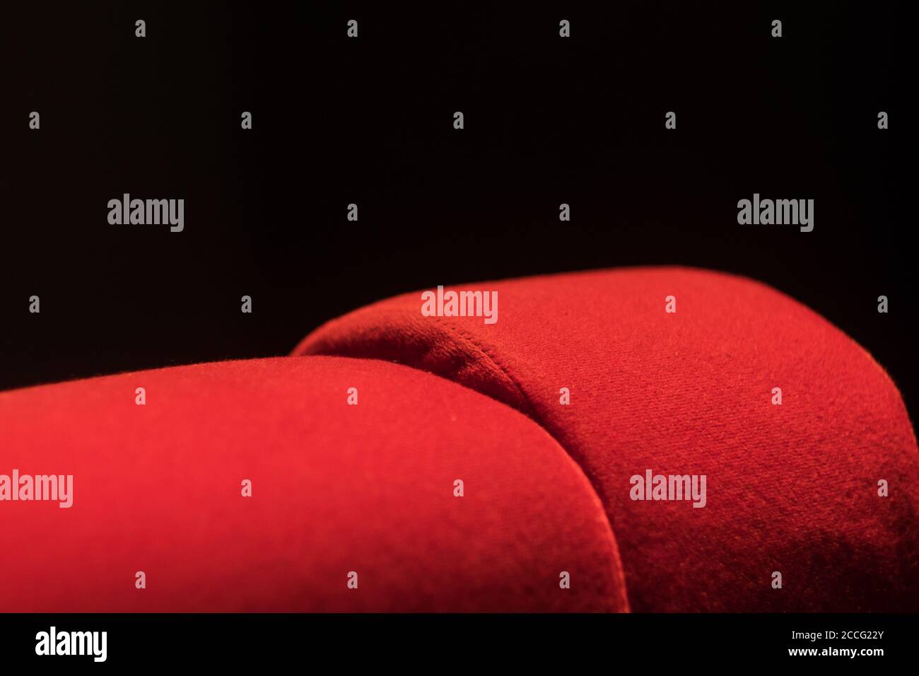 Red seat from a movie theater in Paris, France. Macro shot, sharp details of the velours cinema seat. Stock Photo