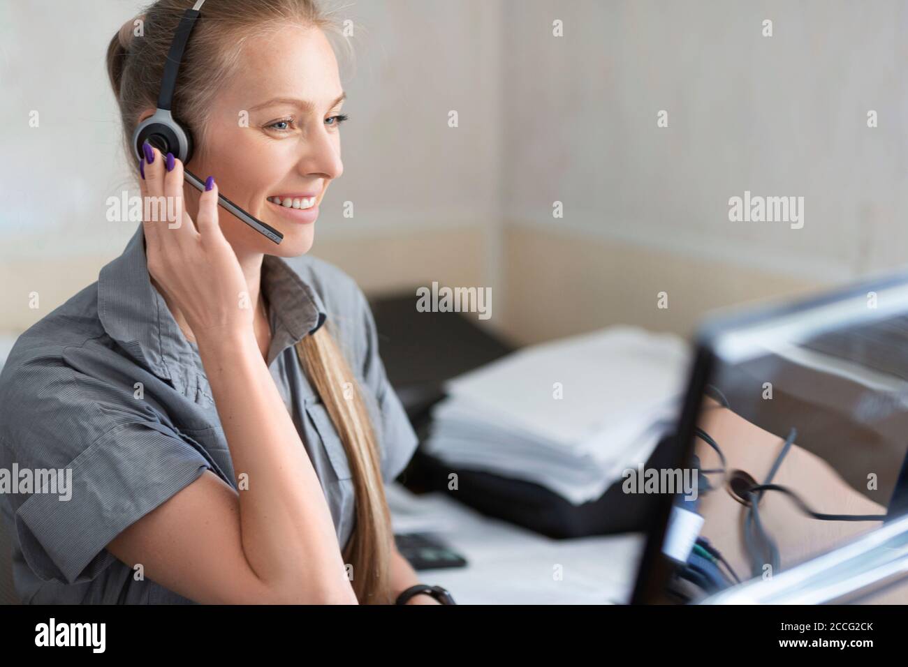 Portrait of a smiley woman with headset working in a call center. Stock Photo