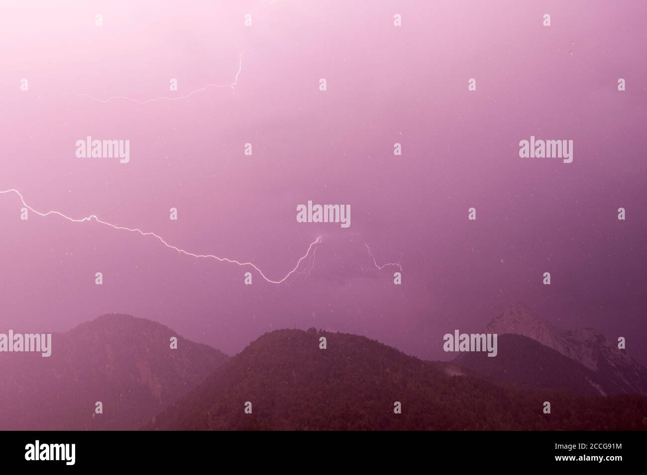 Lightning strike during a strong summer thunderstorm in the Wildsteinkopf near Mittenwald in the Bavarian Alps, with the Wetterstein in the background Stock Photo