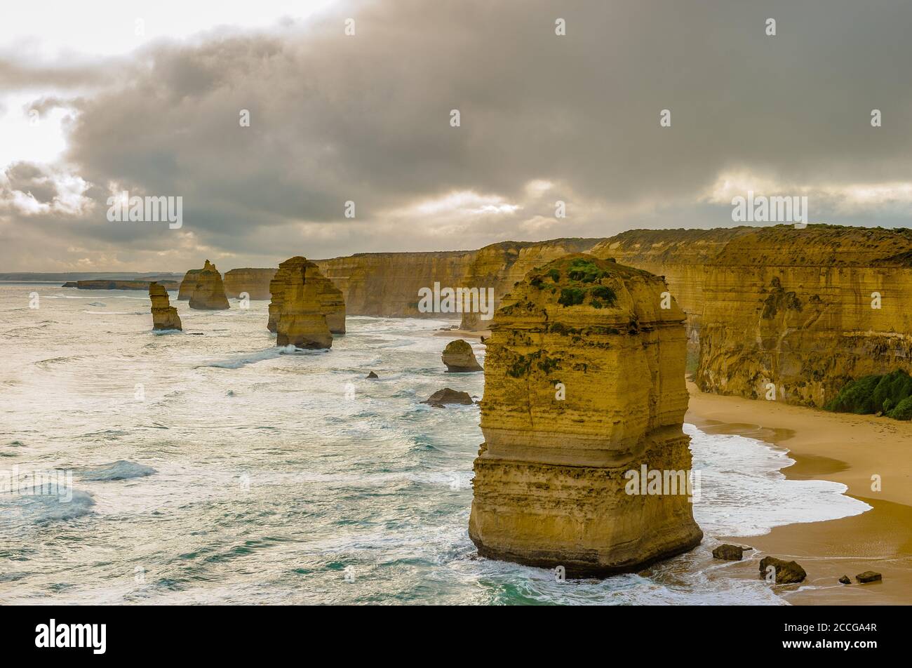 Surviving the tempest,  the remaining Twelve Apostles stacks hug the cliff face on the wild, shoreline of Victoria's Great Ocean Road in Australia. Stock Photo