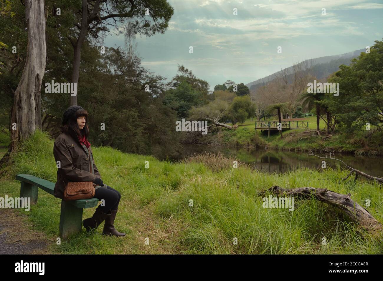 Tourist sitting on a bench on the banks of the youthful Yarra River in the upper reaches of the Yarra Valley in country Victoria in Australia. Stock Photo
