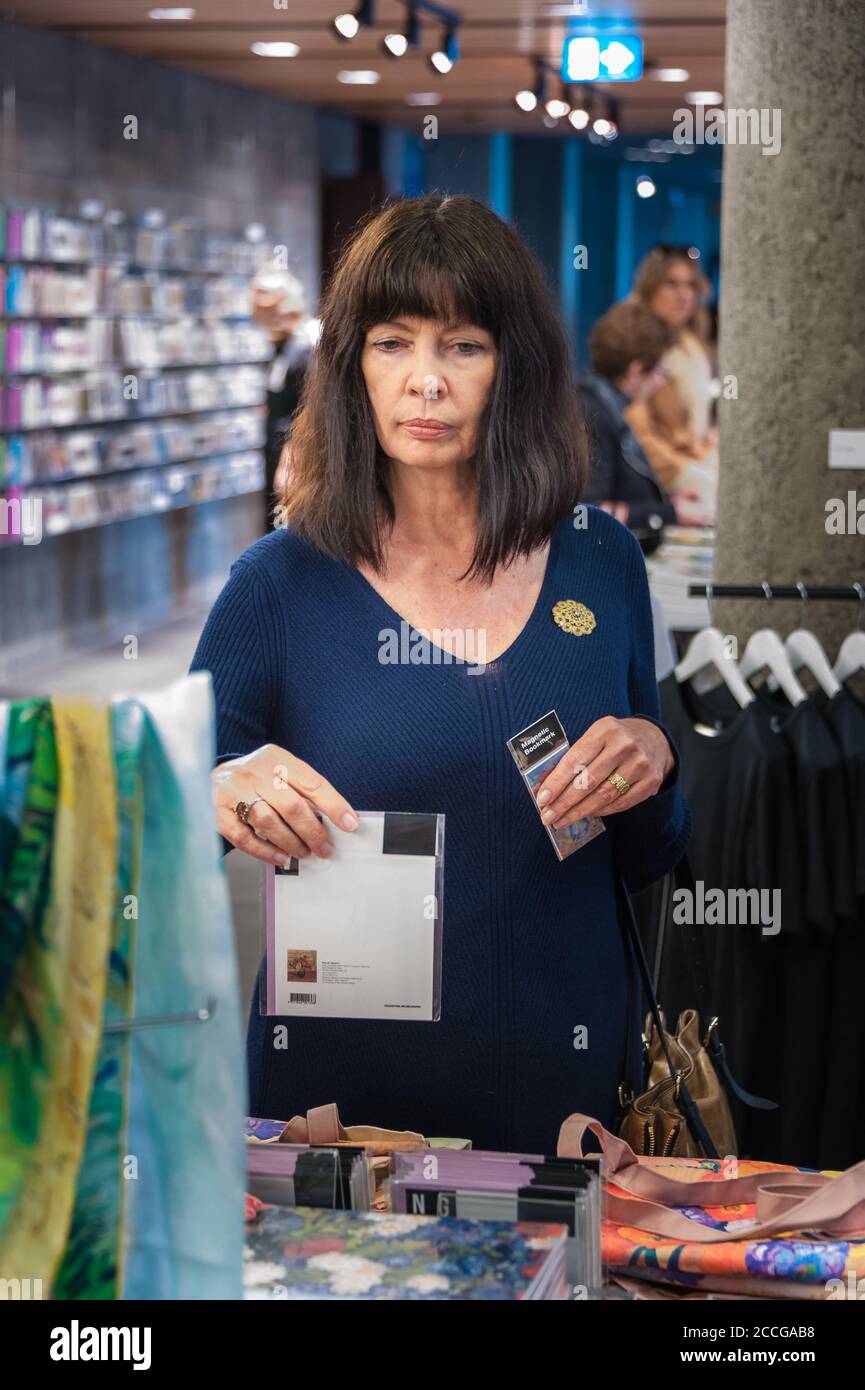 Female tourist, in navy blue woolen dress, souvenir shopping in the National Gallery of Victoria in Melbourne, Australia. Stock Photo