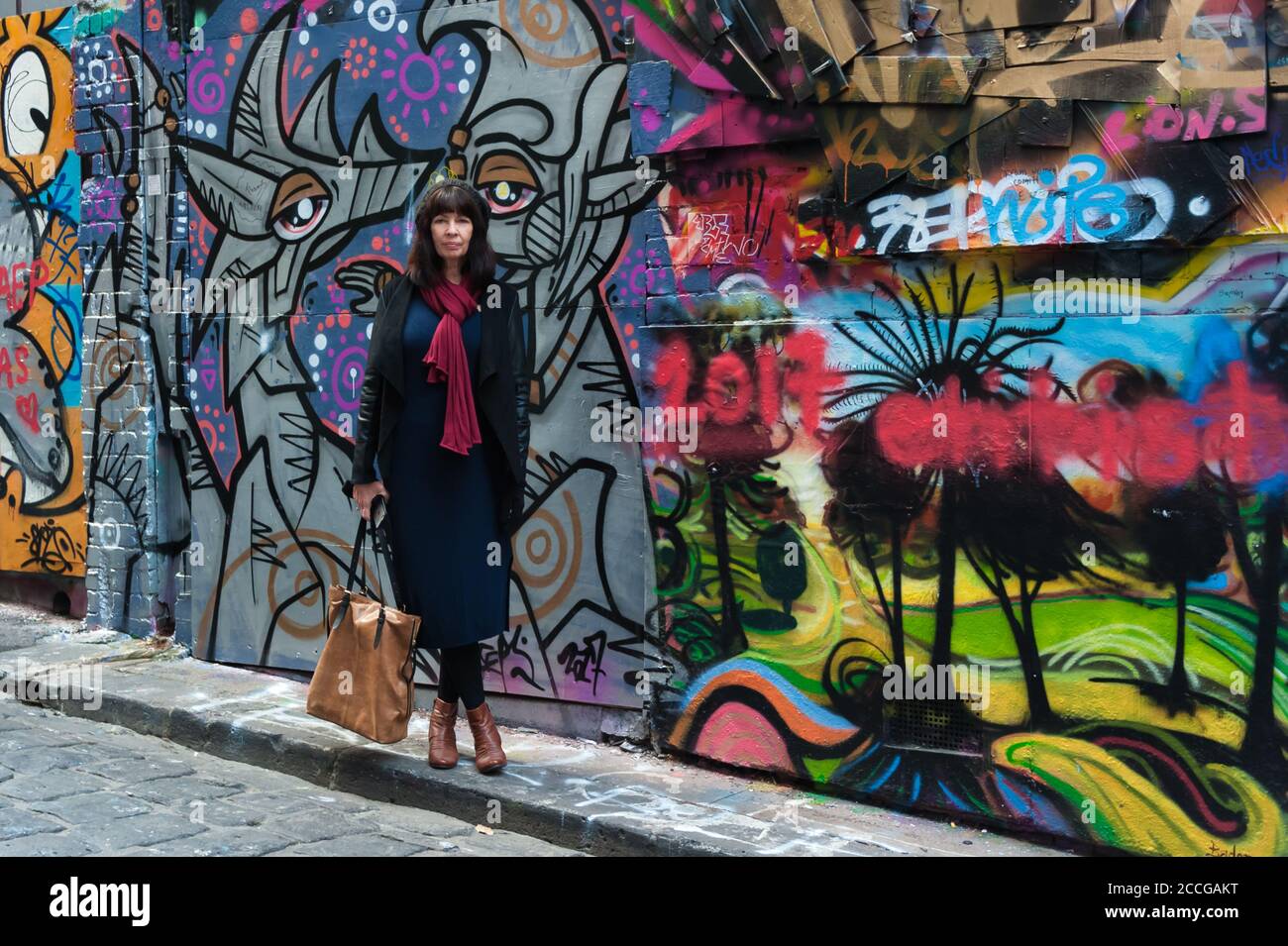 Female tourist pauses beside the colourful, street art along AcDc lane in Melbourne, Victoria, Australia. Stock Photo