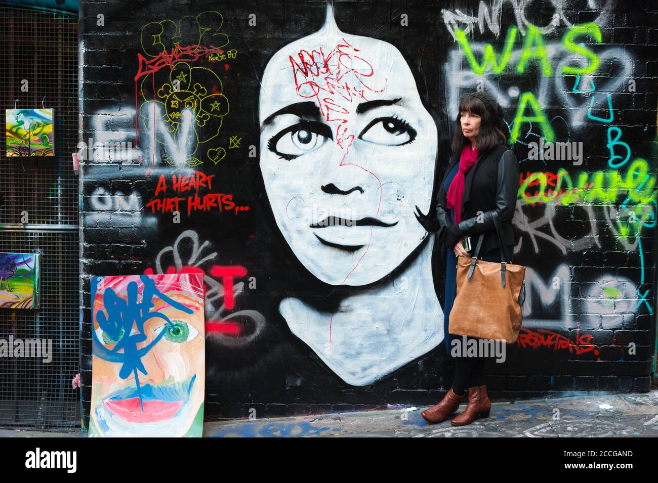 Female tourist pauses beside the colourful, street art along AcDc lane in Melbourne, Victoria, Australia. Stock Photo