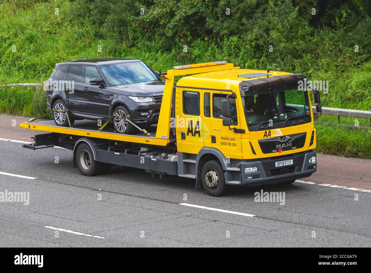 Range Rover on AA Flatbed truck; 24hr emergency breakdown rescue service vehicle; UK Vehicular traffic, transport, modern, saloon cars, south-bound on the 3 lane M6 motorway highway. Stock Photo