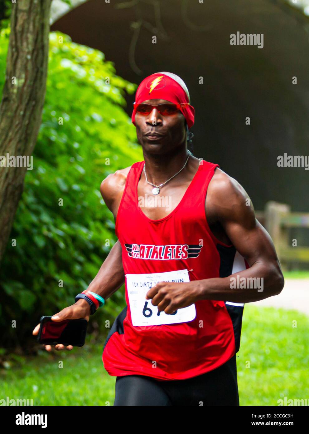Babylon, New York, USA - 12 August 2018: An African American runner with red bandana with the flash sidn on it during the Dirty Sock 10K trail race. Stock Photo