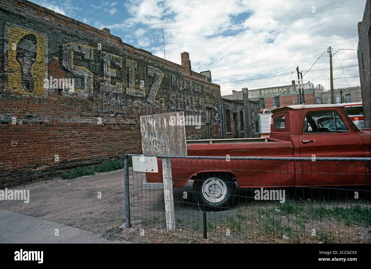 PARKING LOT WITH OLD PAINTED ADVERTISING SIGN IN DOWNTOWN CHEYENNE, WYOMING, USA 1970s Stock Photo