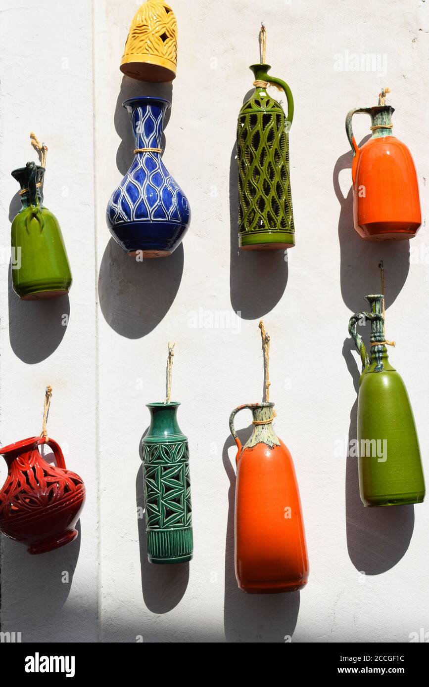 Colored ceramic pots hanging outside a white wall Stock Photo