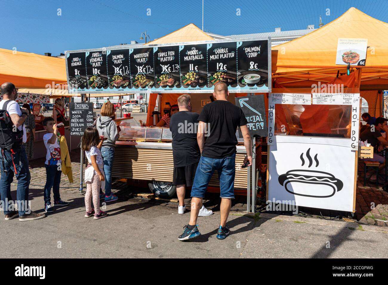 People queuing at seafood vendor's stall for fish dishes in Helsinki Market Square, Finland Stock Photo