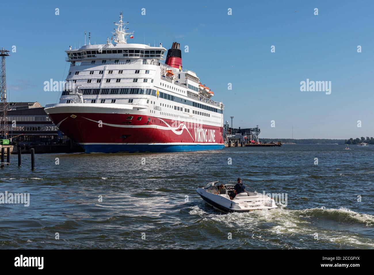 Motorboat and cruise ship M/S Gabriella of Viking Line Shipping Company in front of Katajanokka district, Helsinki, Finland Stock Photo
