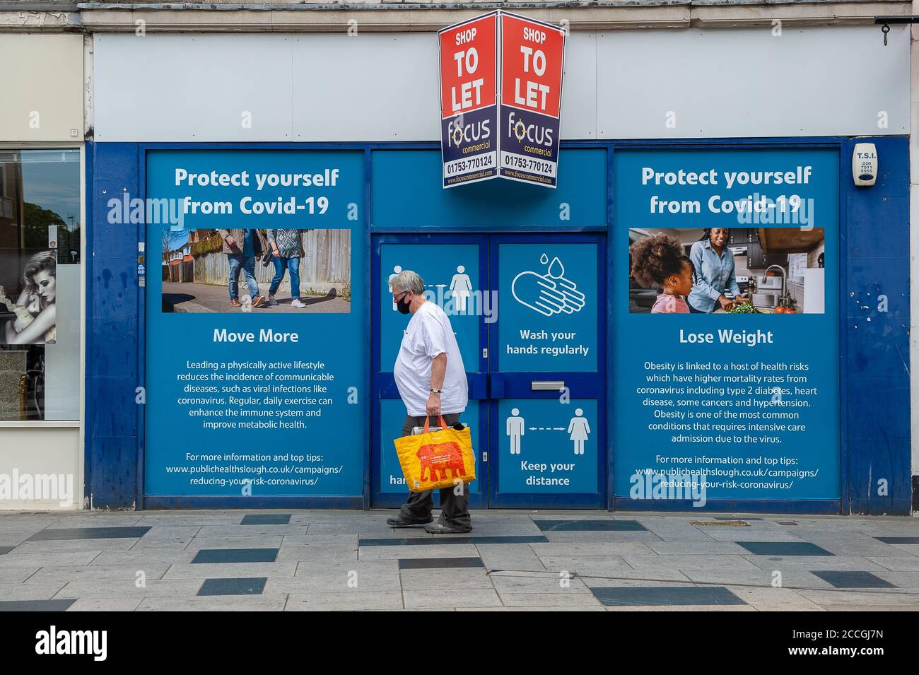 Slough, Berkshire, UK. 22nd August, 2020. A man walks past a public notice in Slough High Street reminding people to keep their weight in check. Slough in Berkshire has been named by Public Health England and the Department for Health and Social Care as a Covid-19 'area of concern' following a recent increase in the number of cases. Credit: Maureen McLean/Alamy Live News Stock Photo