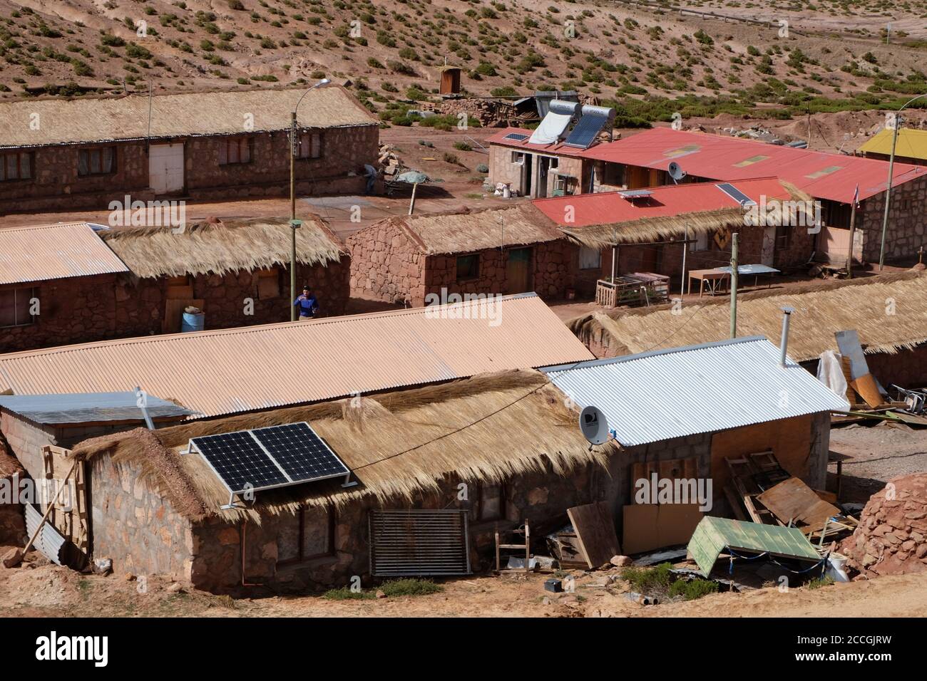 Solar panels and satellite dishes fixed to rooftops of adobe-built and straw-roofed village houses in the high Chilean Andes. Stock Photo