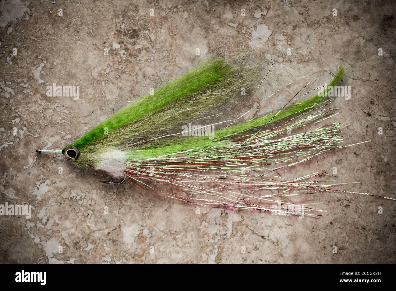 A homemade fishing fly designed for catching pike, Esox lucius. Desaturated colours on a light stone background. Dorset England UK GB Stock Photo