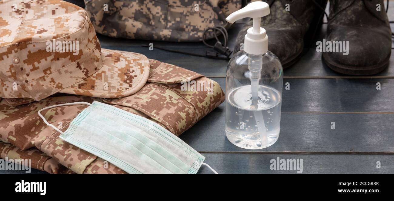 Army coronavirus protection concept. Hand sanitizer, medical protective mask and US army gear on blue color wooden background. Covid 10 outbreak preve Stock Photo