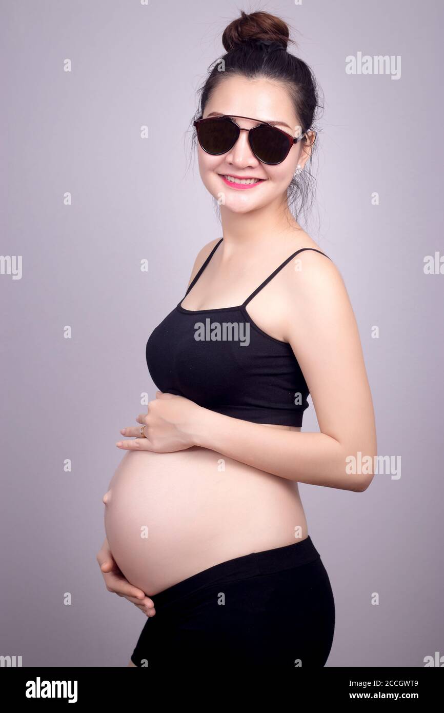 Happy mom concept : Portrait of happy pregnant Asian woman with smile face in black dress with sun glasses. Beautiful Asia female model in her 20s. Stock Photo