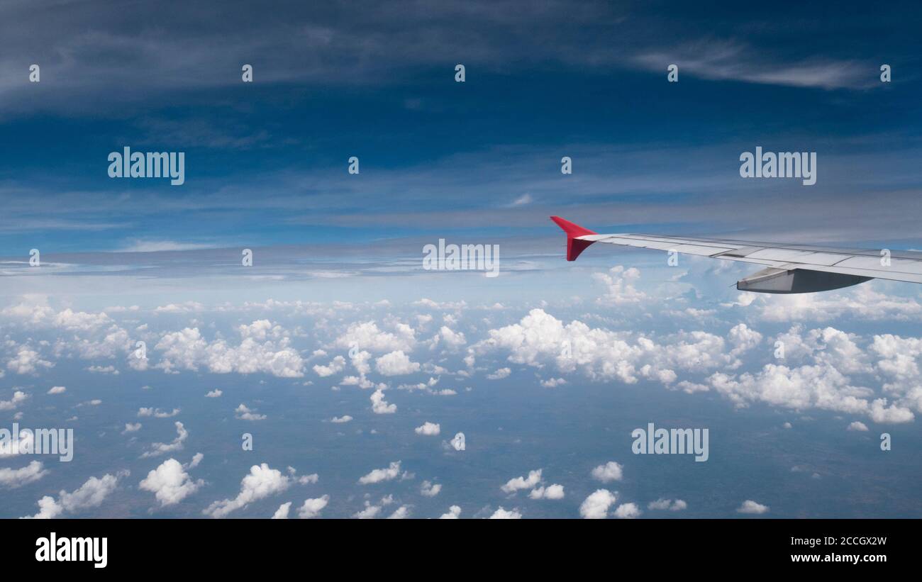 Plane travel concept : View from aircraft window. Clouds and blue sky under airplane wing as seen through window of an airplane in wide angel with cop Stock Photo