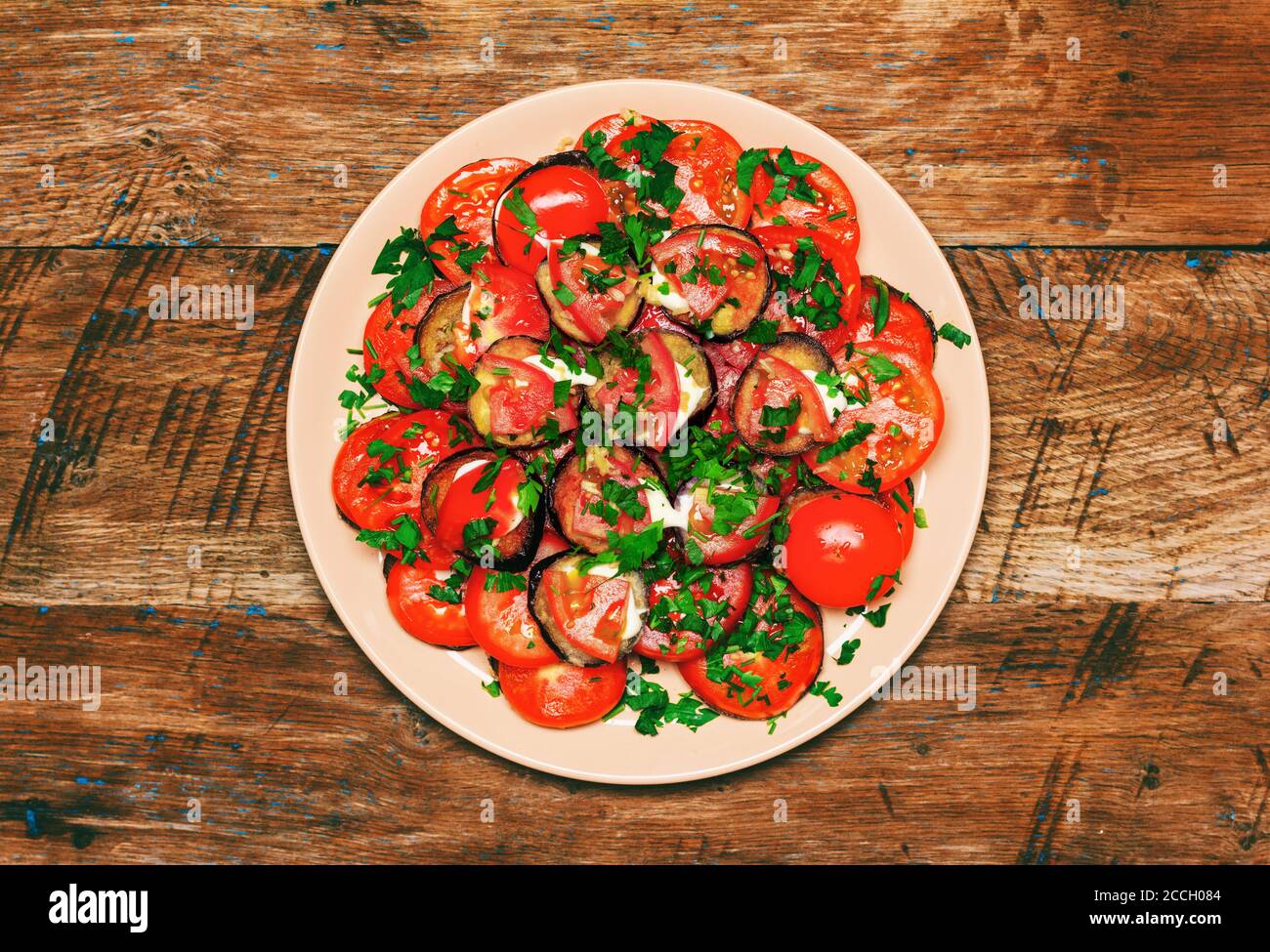 fried eggplant with tomato, garlic and mayonnaise on a wooden background, top view close-up Stock Photo