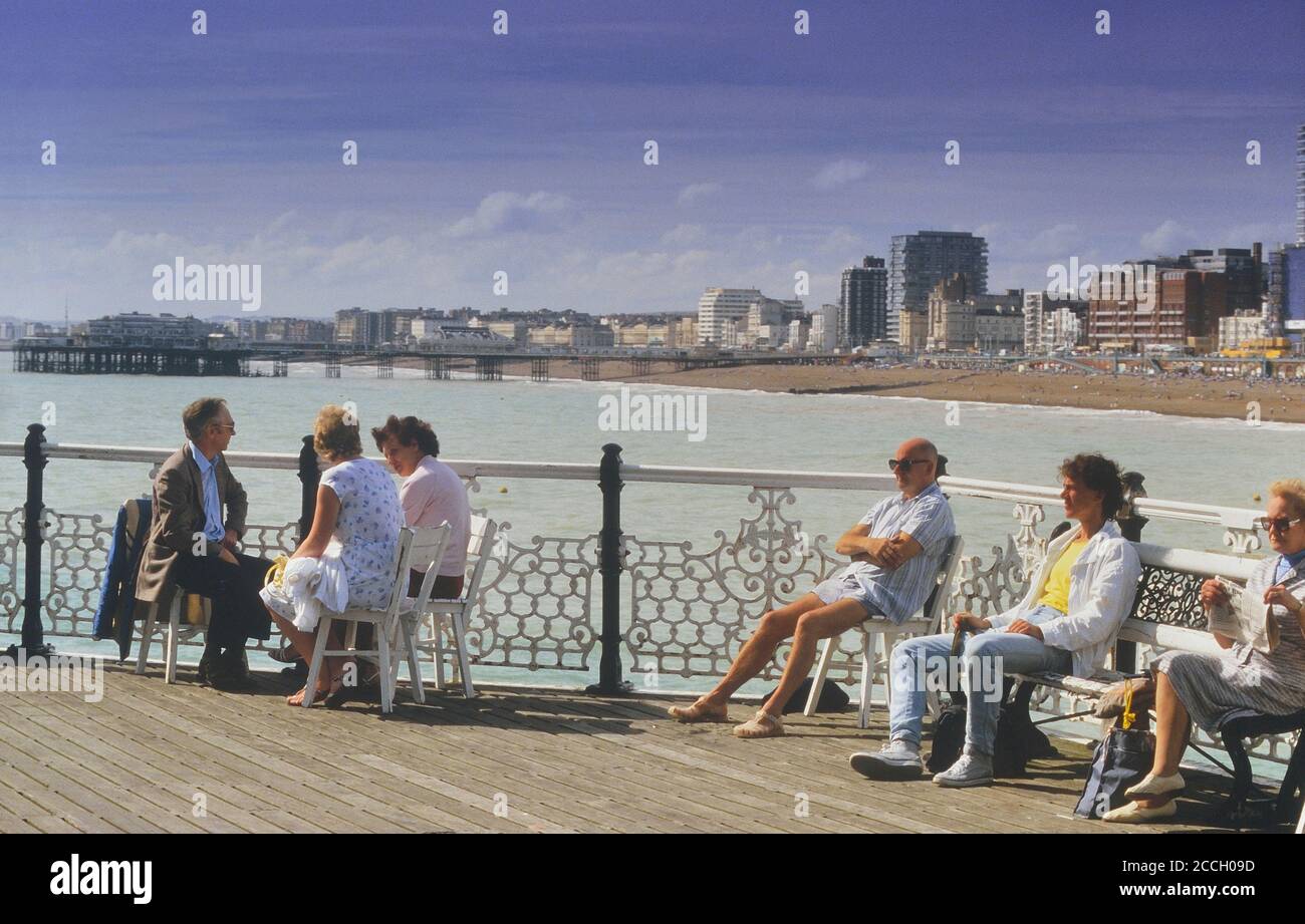 Tourists on the Palace pier with the West pier in the background. Brighton, East Sussex, England, UK. Circa 1980's Stock Photo