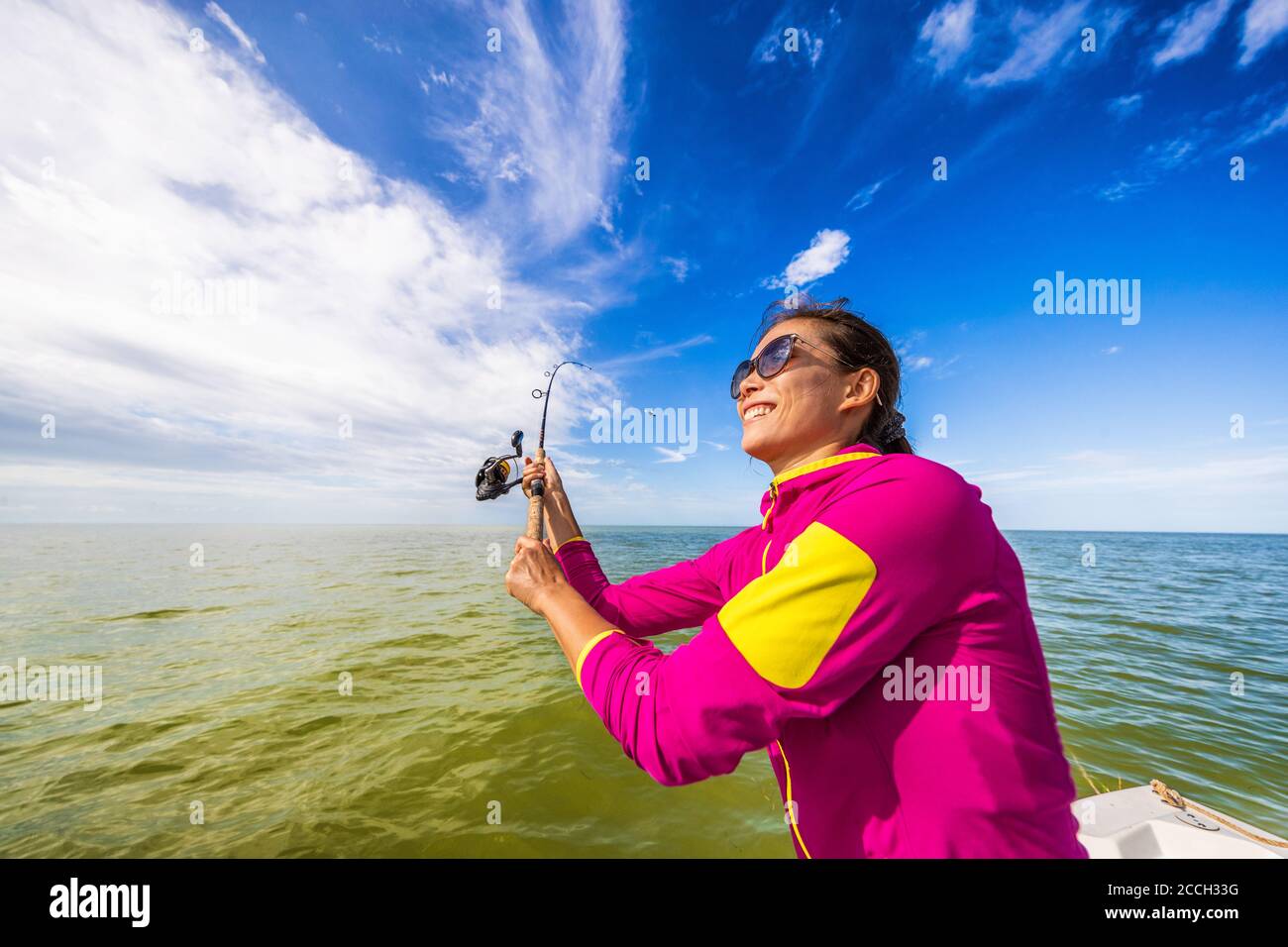 Fishing woman having fun learning to fish throwing casting line on ocean. Tourist on boat excursion Stock Photo