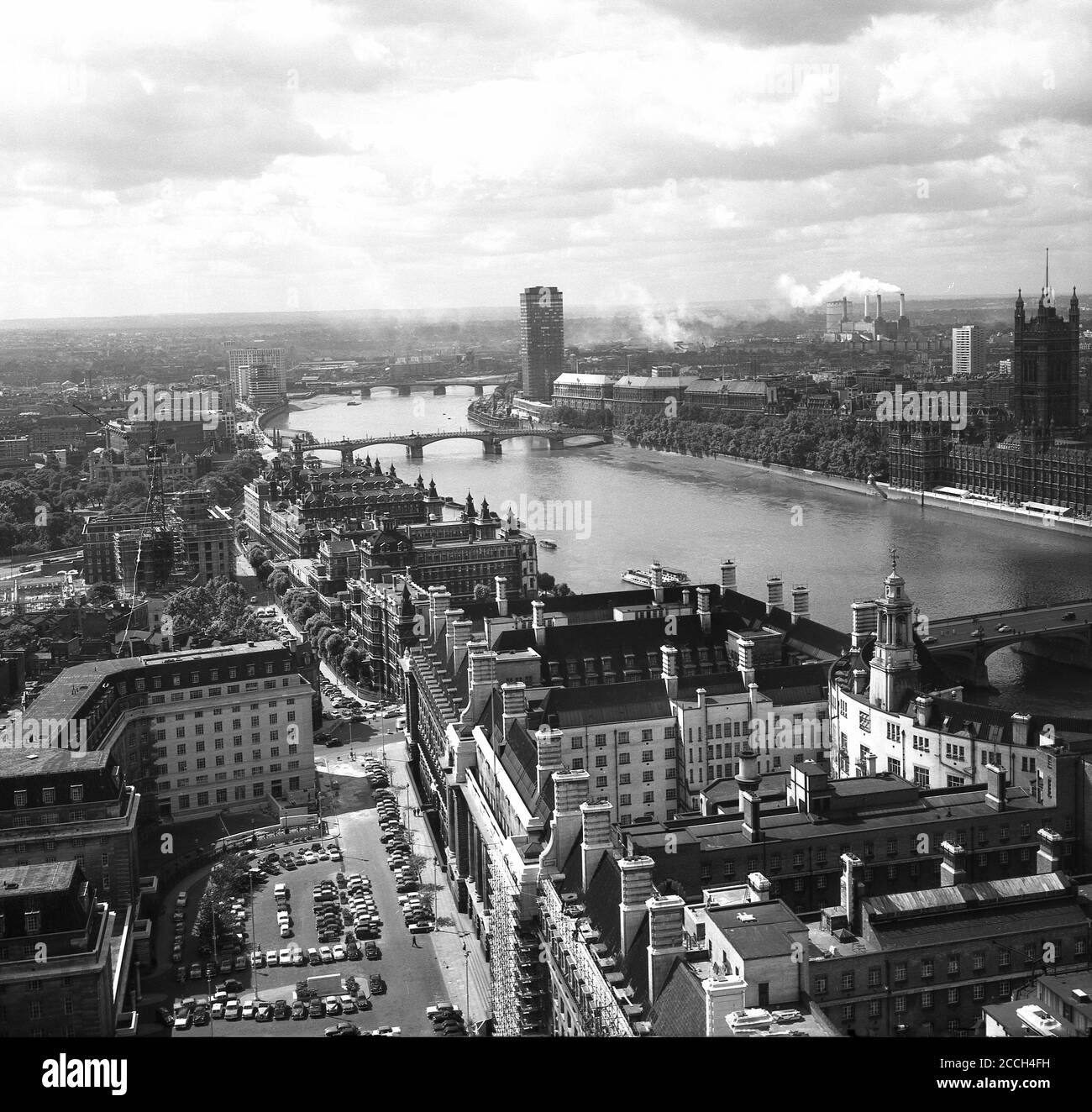 1960s, historical, Post-war view of the skyline of the city of London, as seen from the South across the river Thames. A new 'modern' high-rise tower block, of which many were built in this era, can be seen by the river, its great height above all the other buildings already leaving a distinctive mark on the surrounding landscape and skyline.  The smoking chimneys of Battersea Power station can be seen in the distance, with the Palace of Westimnister, the two Houses of the UK Pariament on the far right. Stock Photo