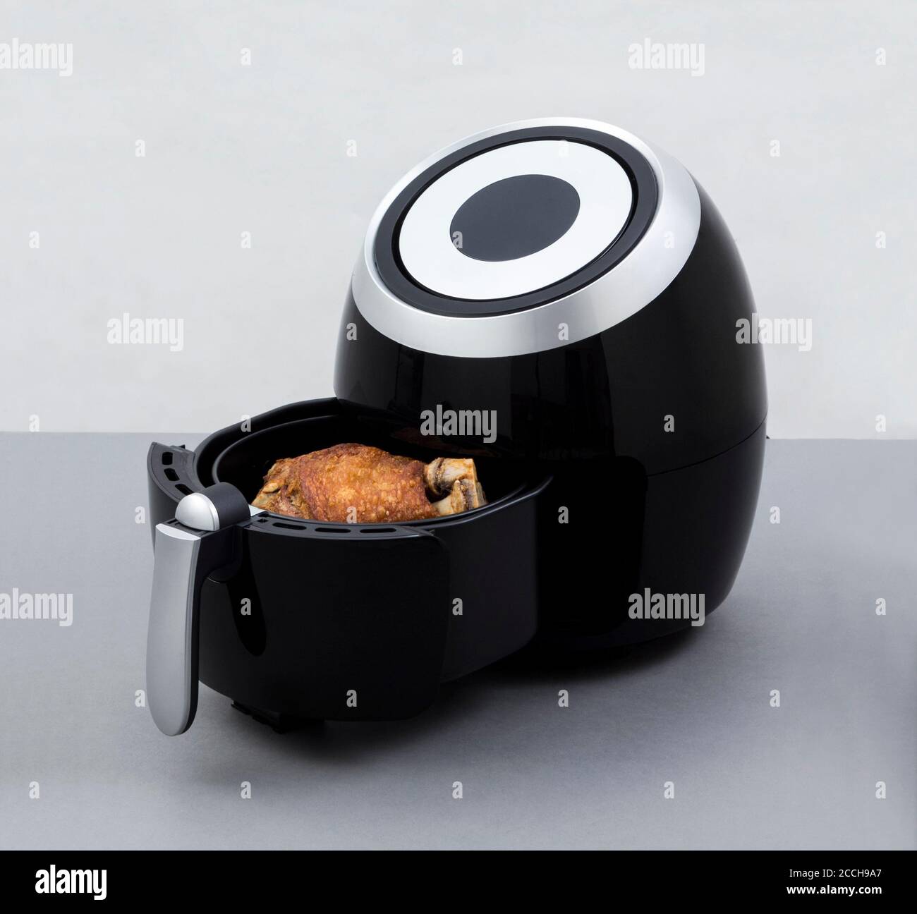 Air fryer machine with fried pork knuckle on white background Stock