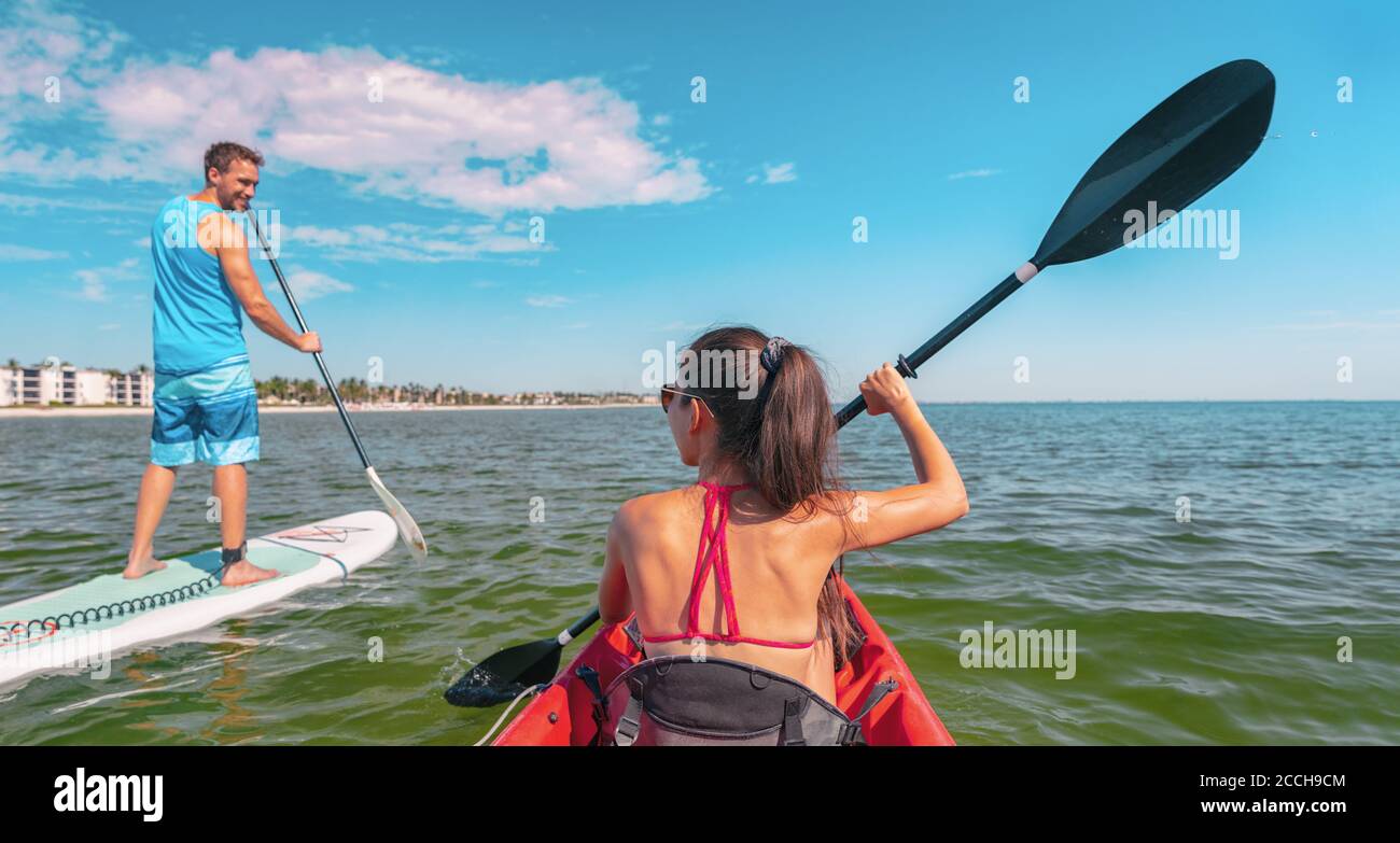 Couple kayaking and paddle boarding fitness man in ocean Paddleboard beach people on stand-up paddle boards surfing in Tourists kayakers woman and man Stock Photo
