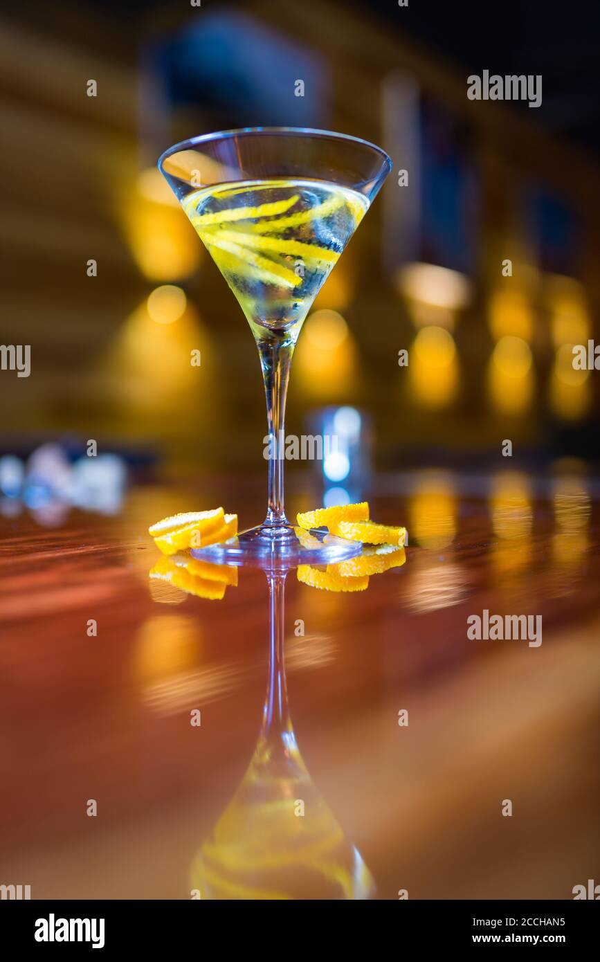 A classy craft cocktail in a martini glass with a lemon rind garnish in a sophisticated, modern bar setting Stock Photo