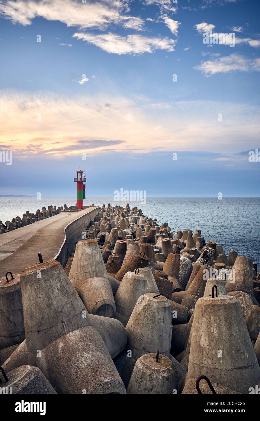 Pier with lighthouse protected by concrete breakwater tetrapods at sunset, Swinoujscie, Poland. Stock Photo