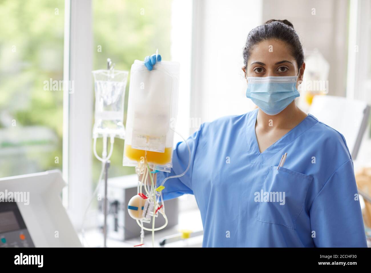 Portrait of nurse in uniform standing with dropper and looking at camera she working at hospital Stock Photo