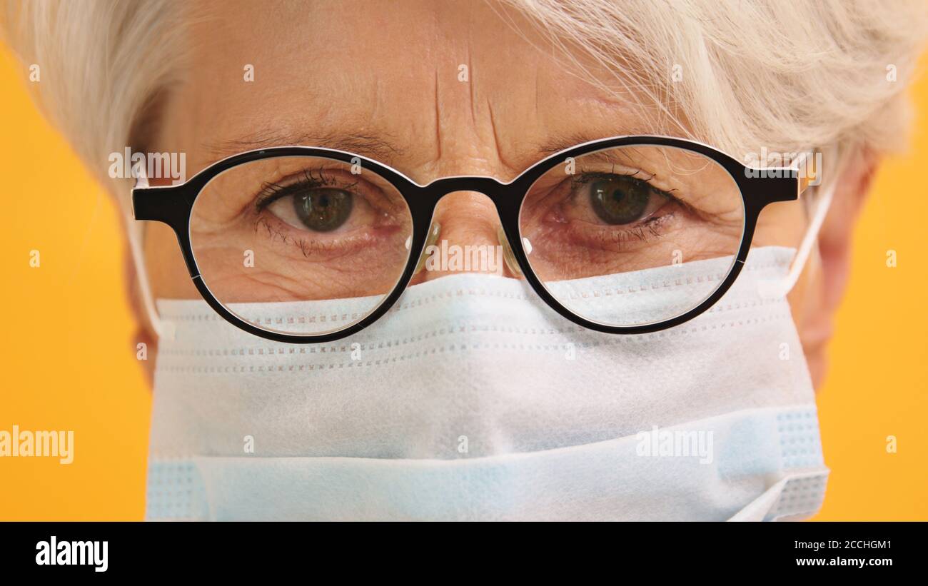 Close up shot of sad old woman with glasses and medical mask. Protect vulnerable people. High quality photo Stock Photo
