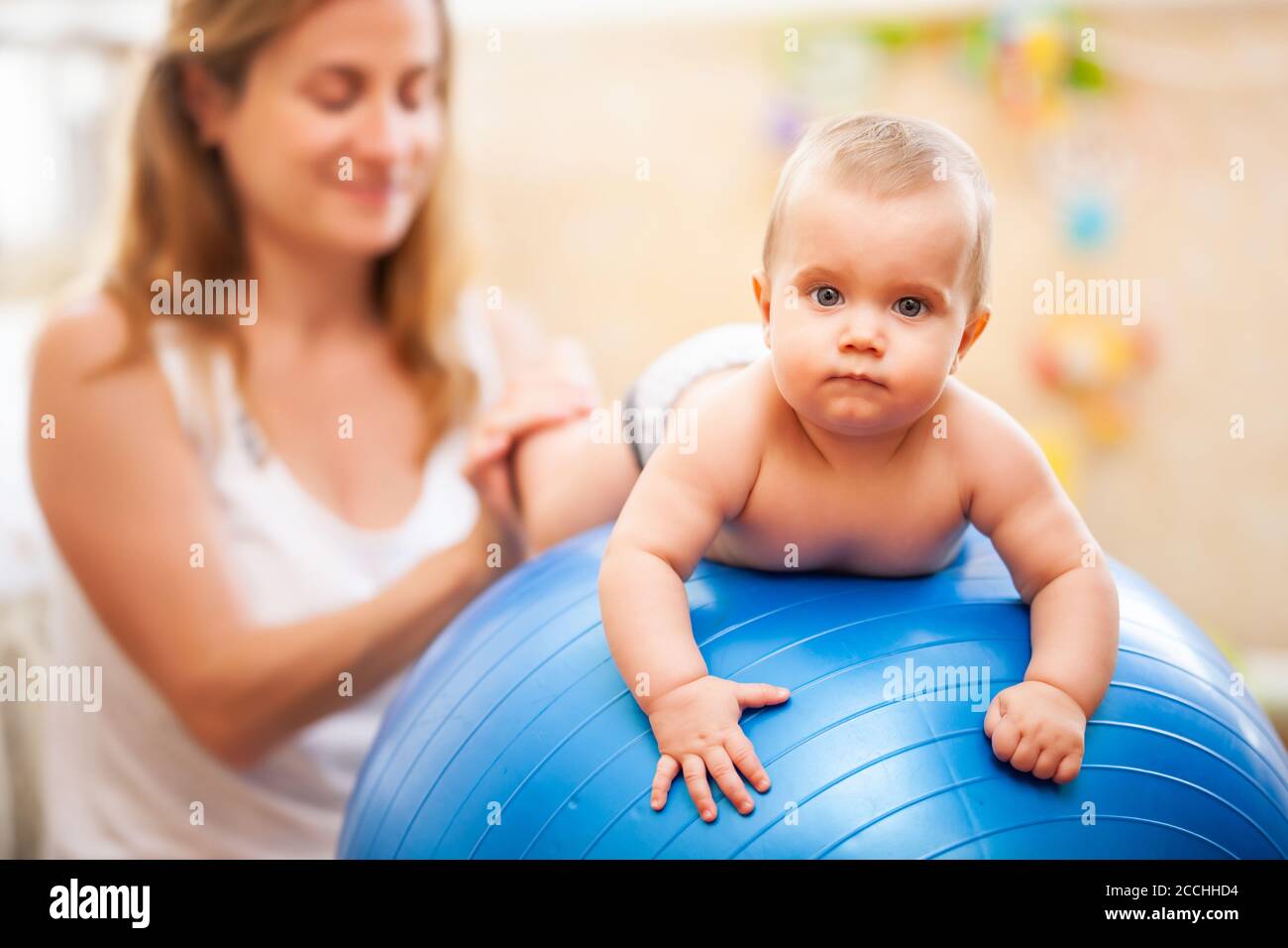 Side view of young caucasian mother helping little baby wearing diaper