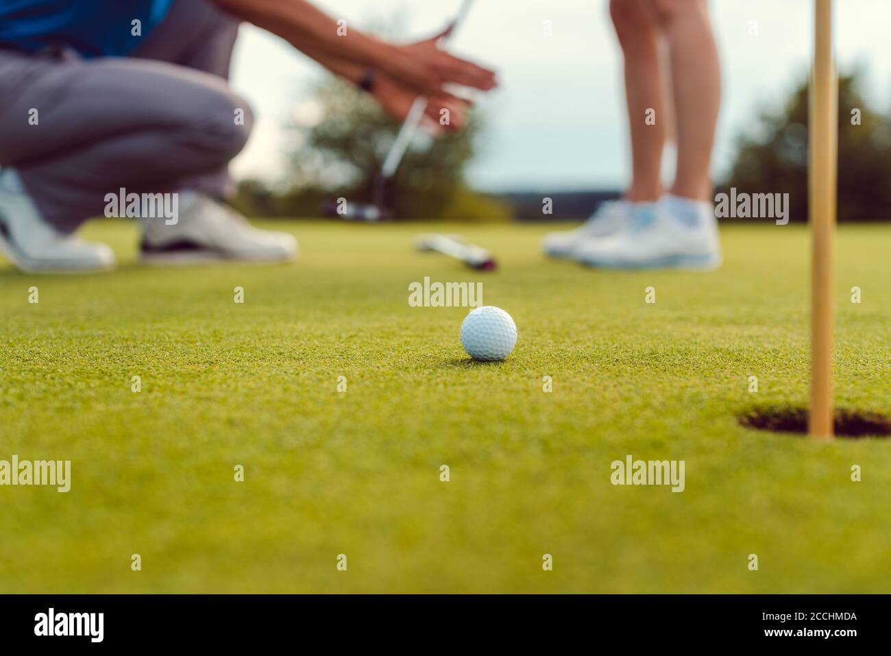 Pro on golf course teaching a woman how to put Stock Photo