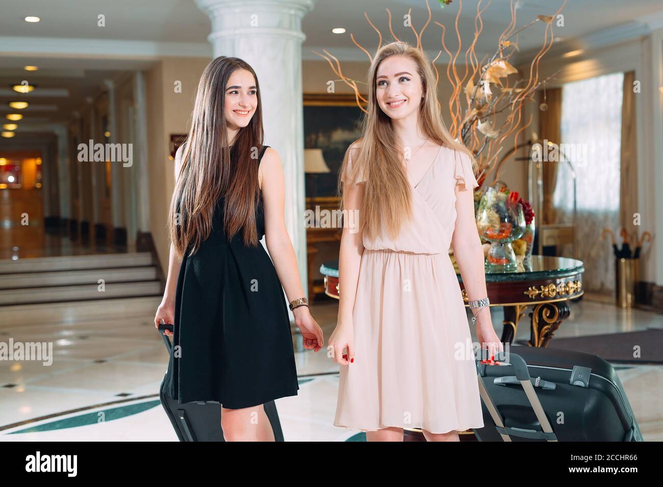 Young girls near reception desk in hotel. Young girls comes to the hotel. Stock Photo