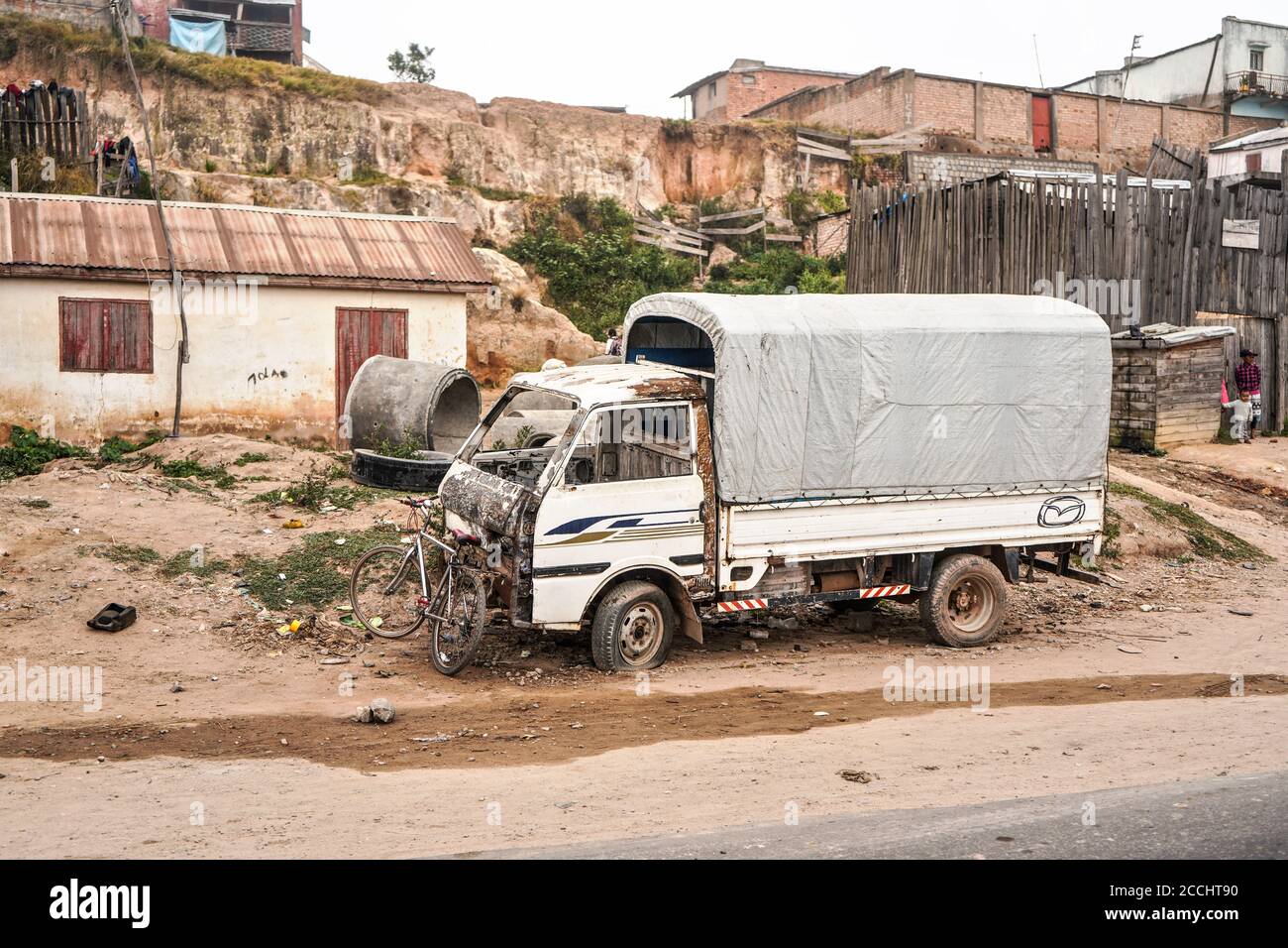 Antananarivo, Madagascar - May 07, 2019: Bicycle leaning on broken truck hood, near main road, garbage on ground - typical scene - as most parts of Ma Stock Photo