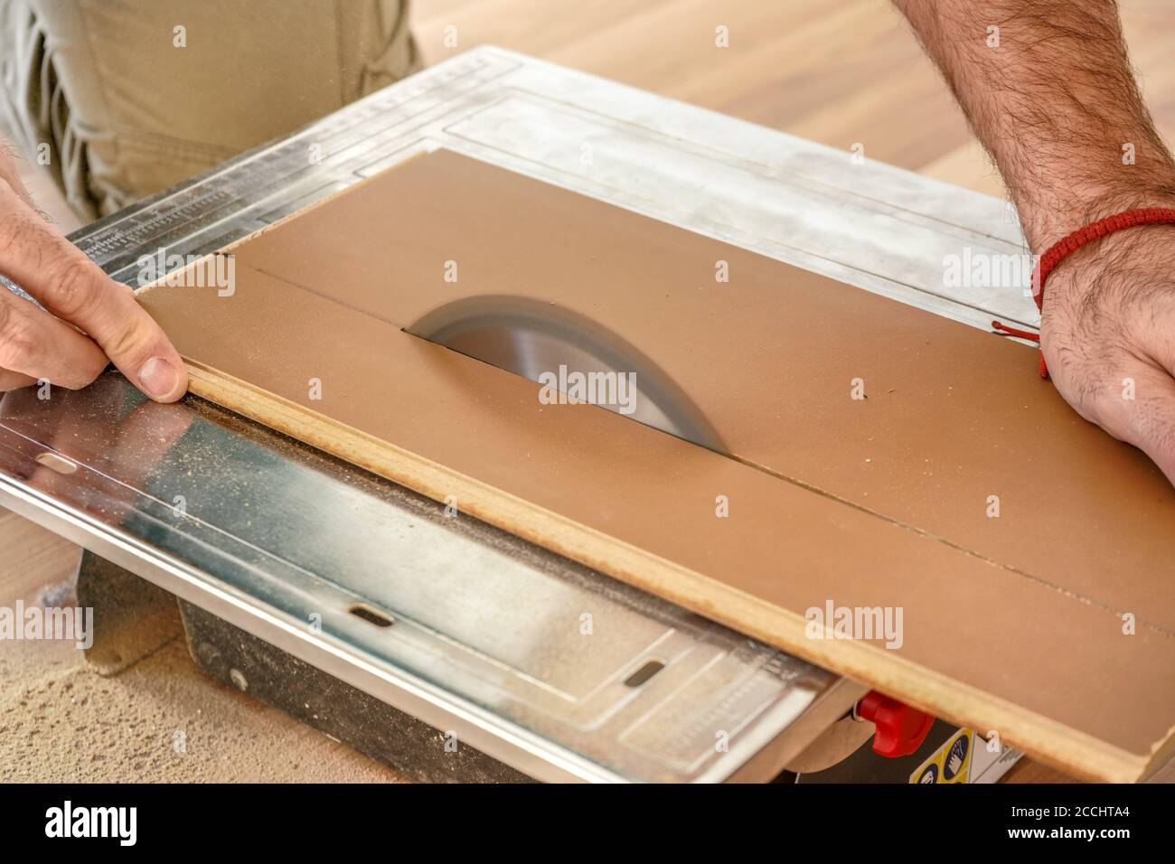 Man cutting laminate floor boards on circular saw, detail on hands