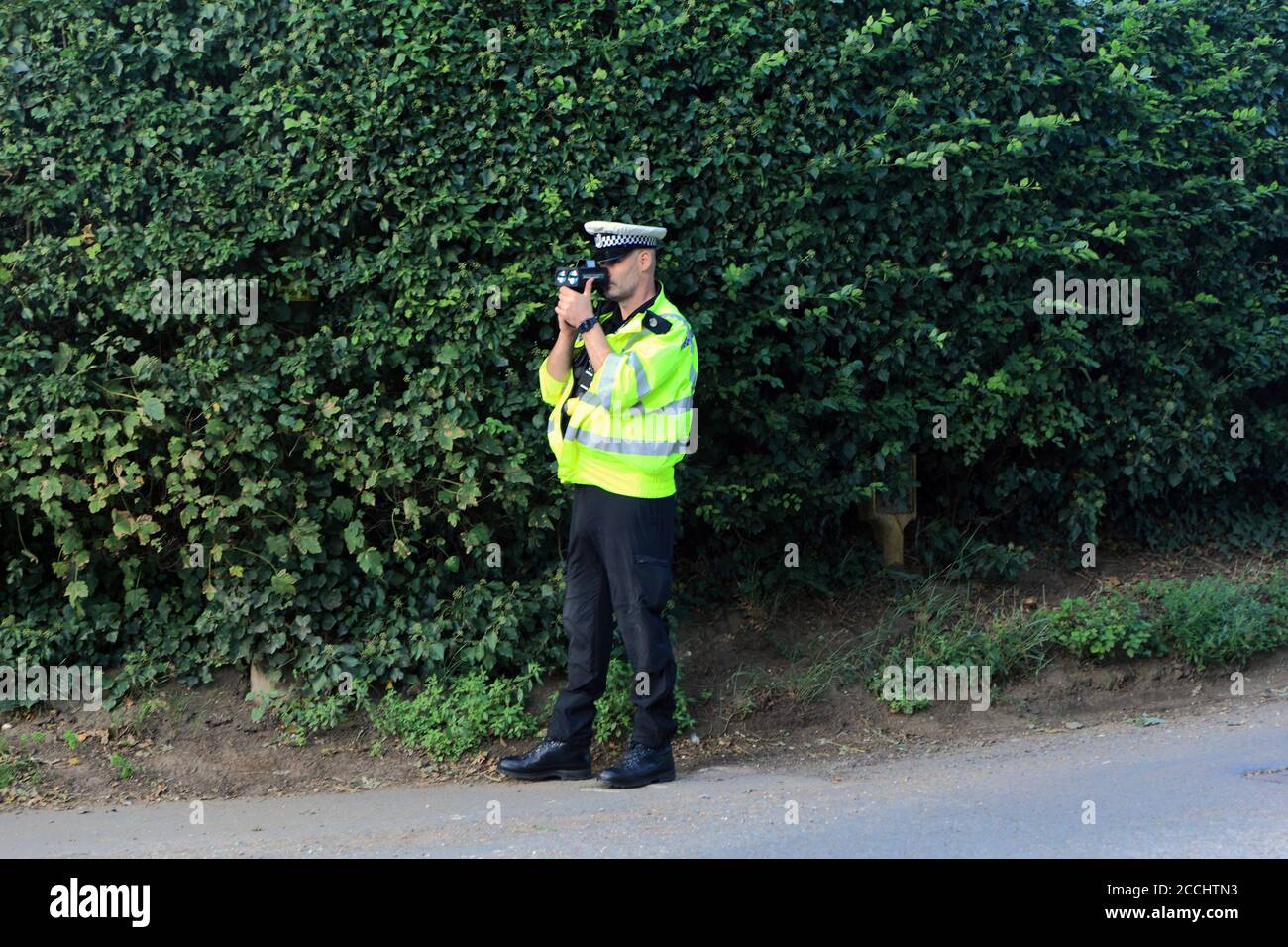 Policeman, operating speed camera, hand held, roadside, speed trap, for vehicles, Norfolk, England, UK Stock Photo