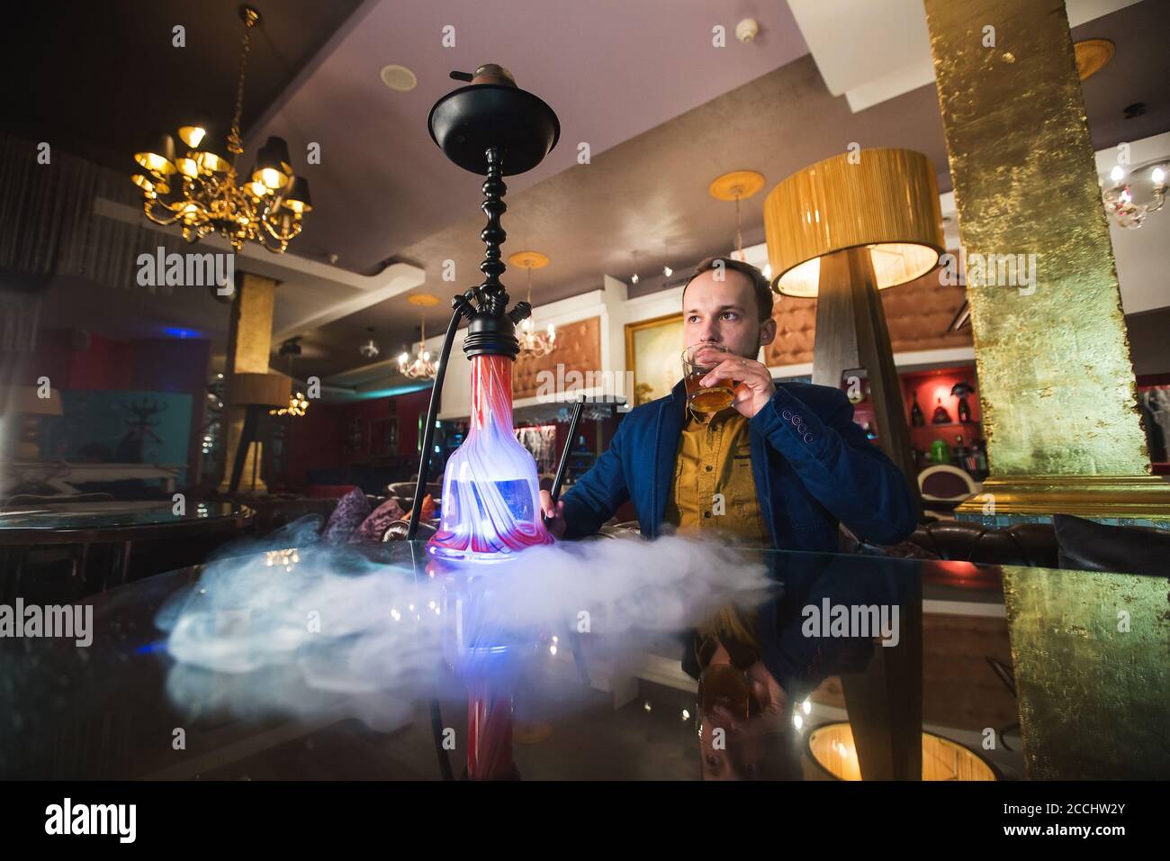 Smoking hookah in a cafe. Man is blowing smoke. Stock Photo