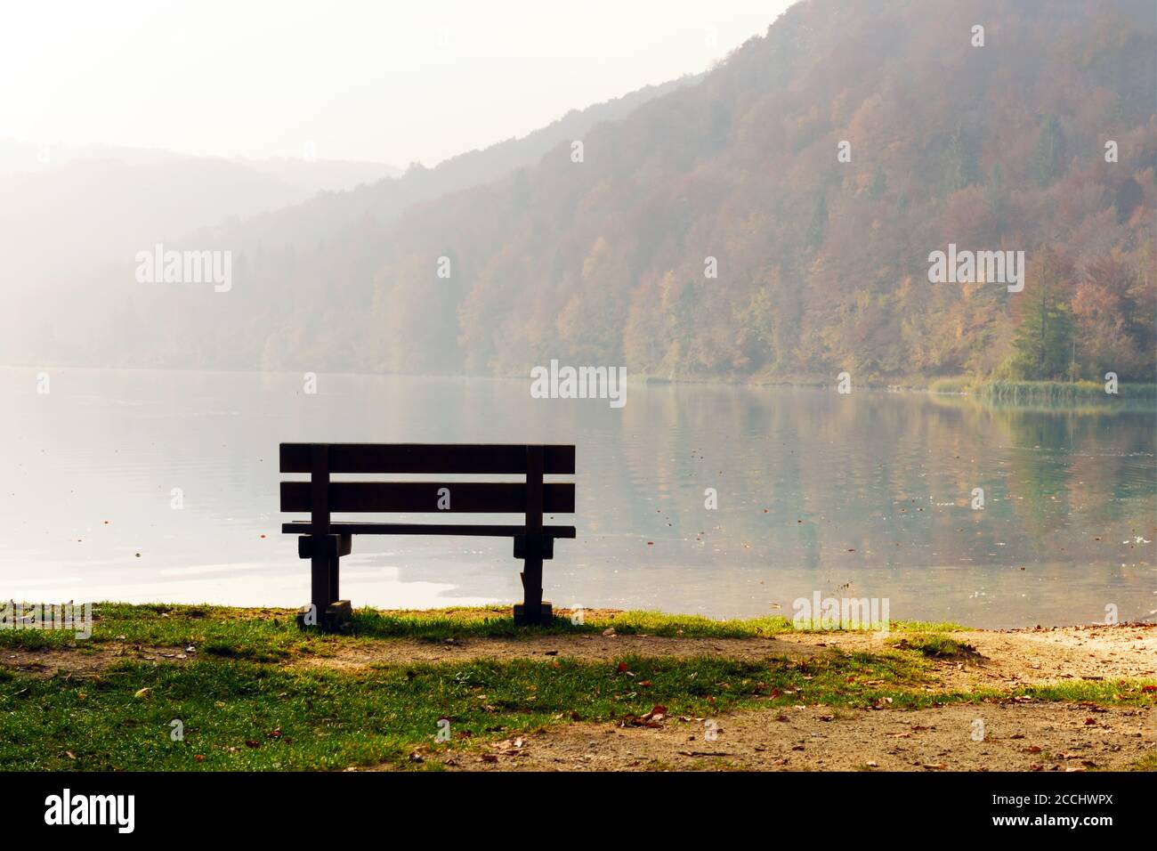 Morning fog on amazing Plitvice lakes. Wooden bench on lake coast. Plitvice National Park, Croatia. Landscape photography Stock Photo