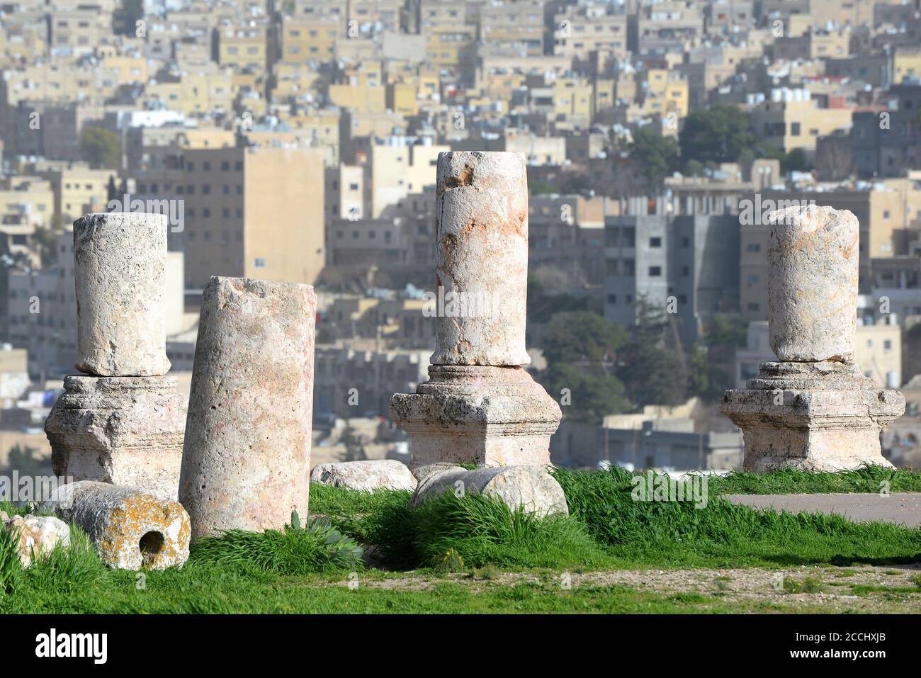 Ruins of Roman Corinthian columns in the Citadel in Amman, Jordan. Blurred and out of focus background showing Amman city skyline. Stock Photo