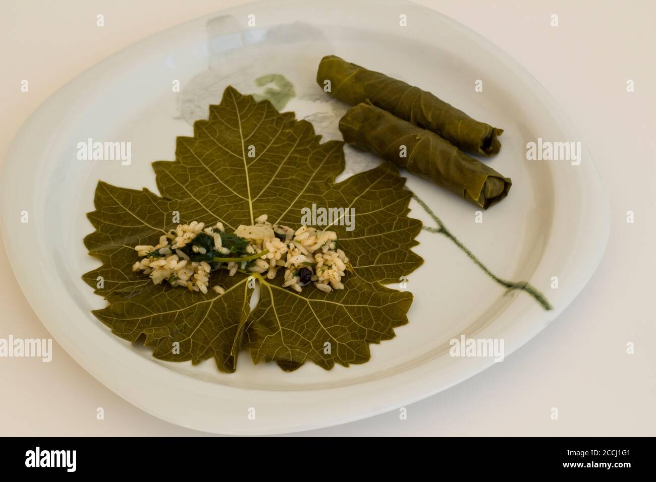 Wraps,rolling of wet grape leaves in white plate,Traditional Turkish Food preparation,above view Stock Photo