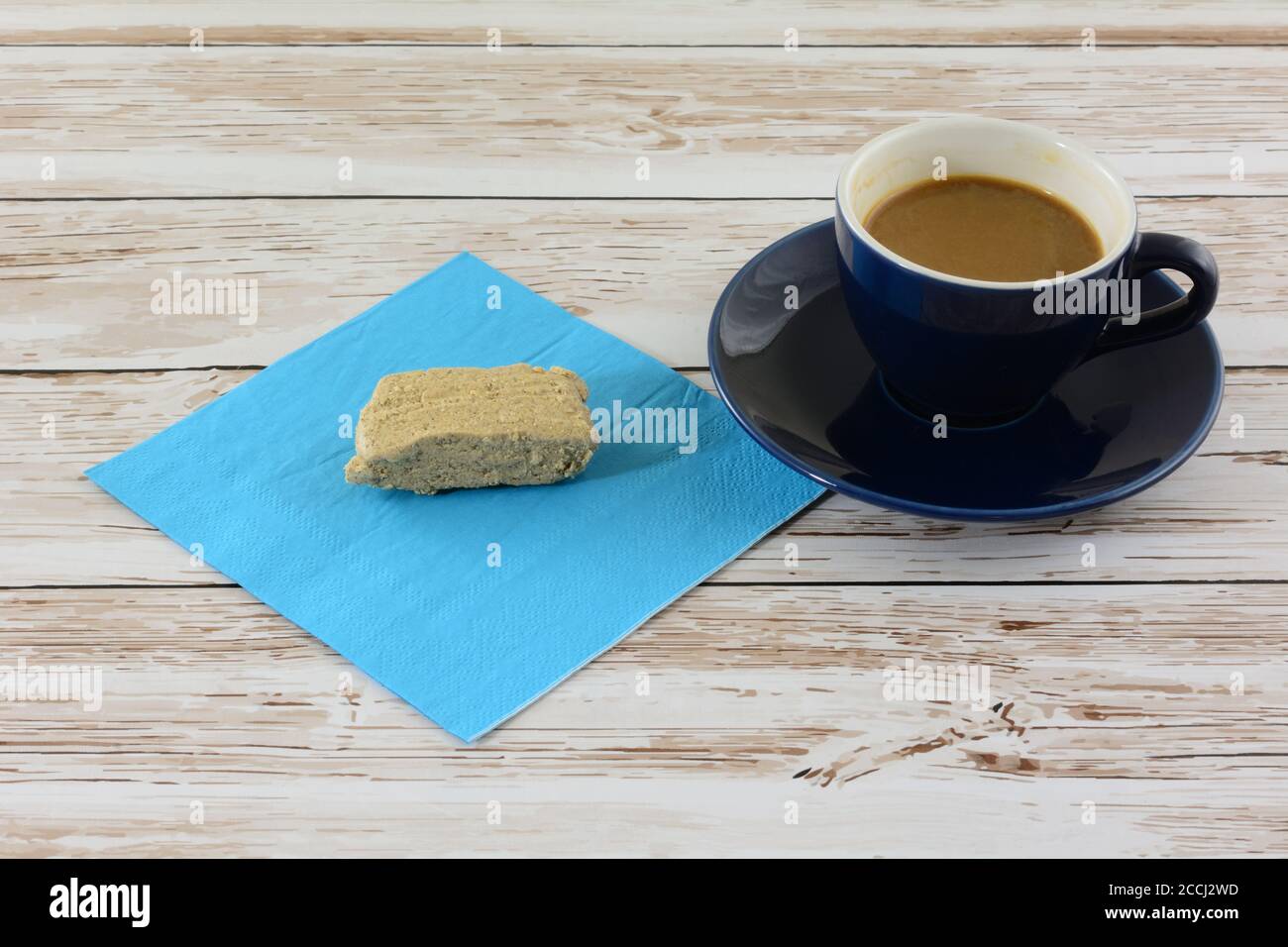 Ground sesame halva snack bar on blue napkin and demi tasse cup of coffee with cream Stock Photo