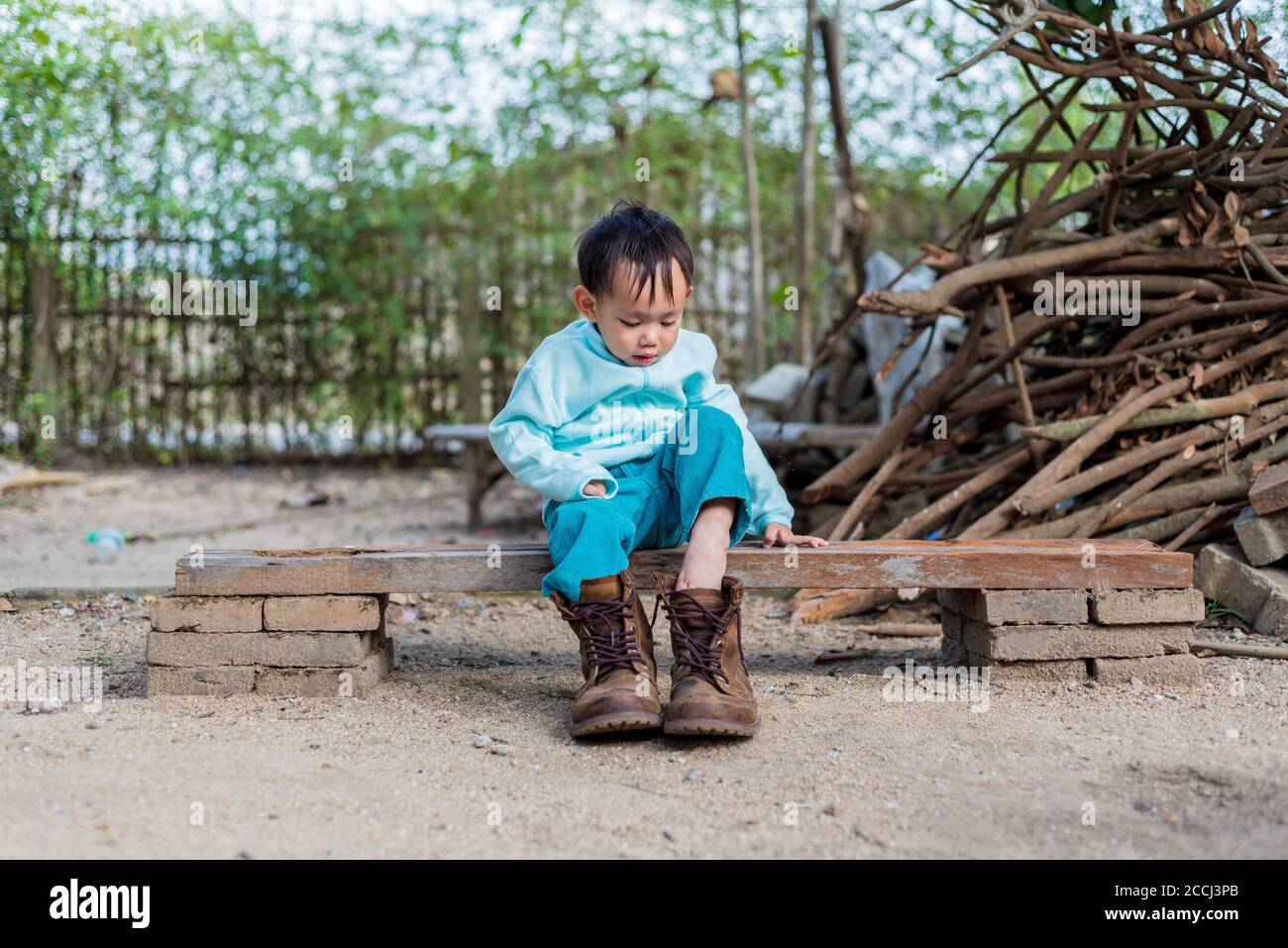 Asian baby boy try to wearing father boots Stock Photo