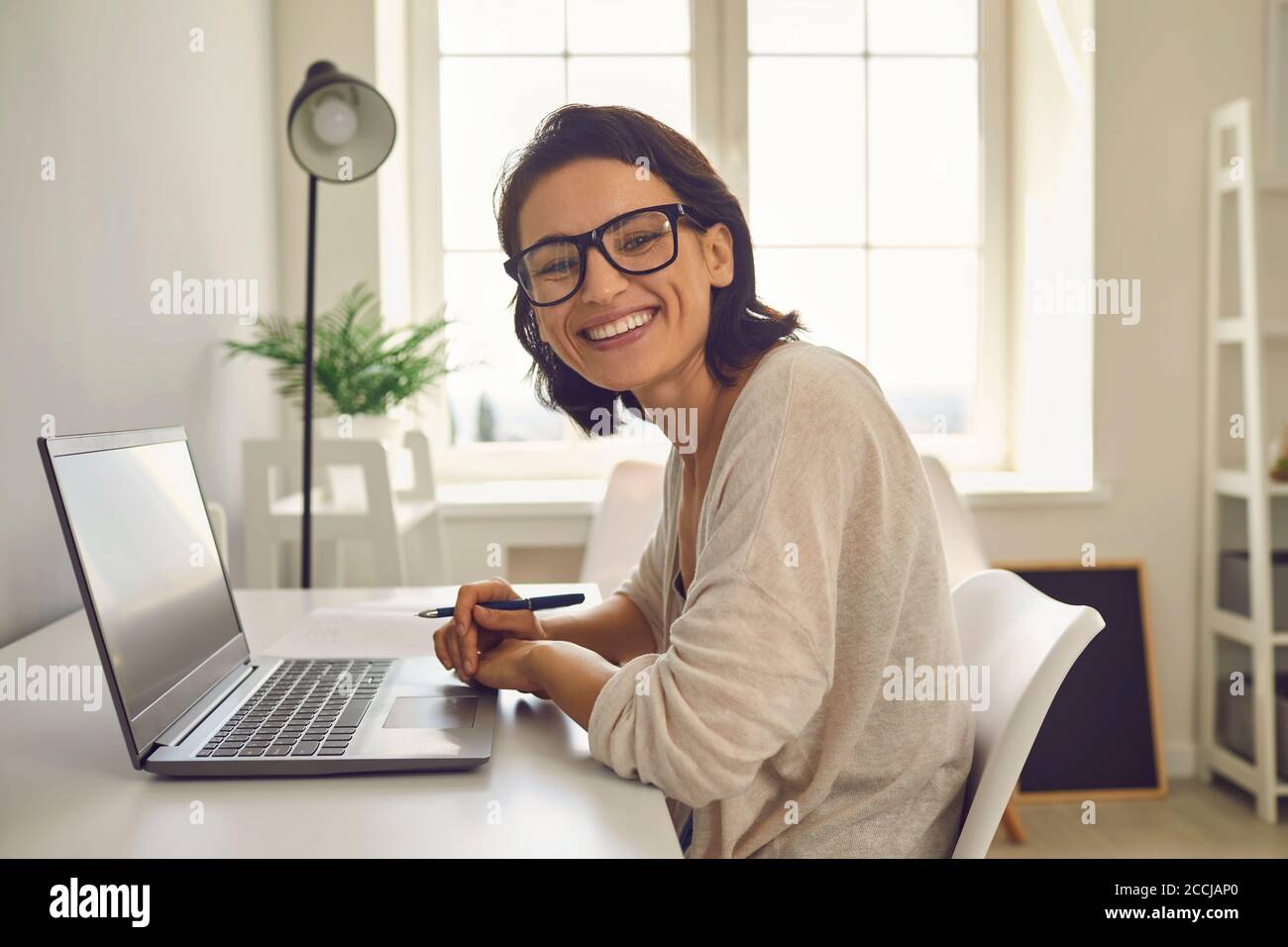 Working from home. Businesswoman taking part in online conference from home office. Happy freelancer using laptop Stock Photo