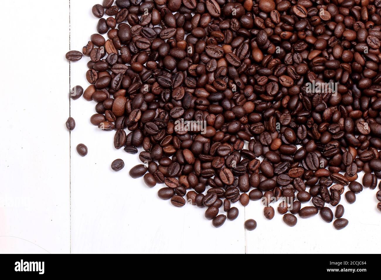 a collection of roasted coffee beans with a third of the top of a whitewashed wooden base Stock Photo