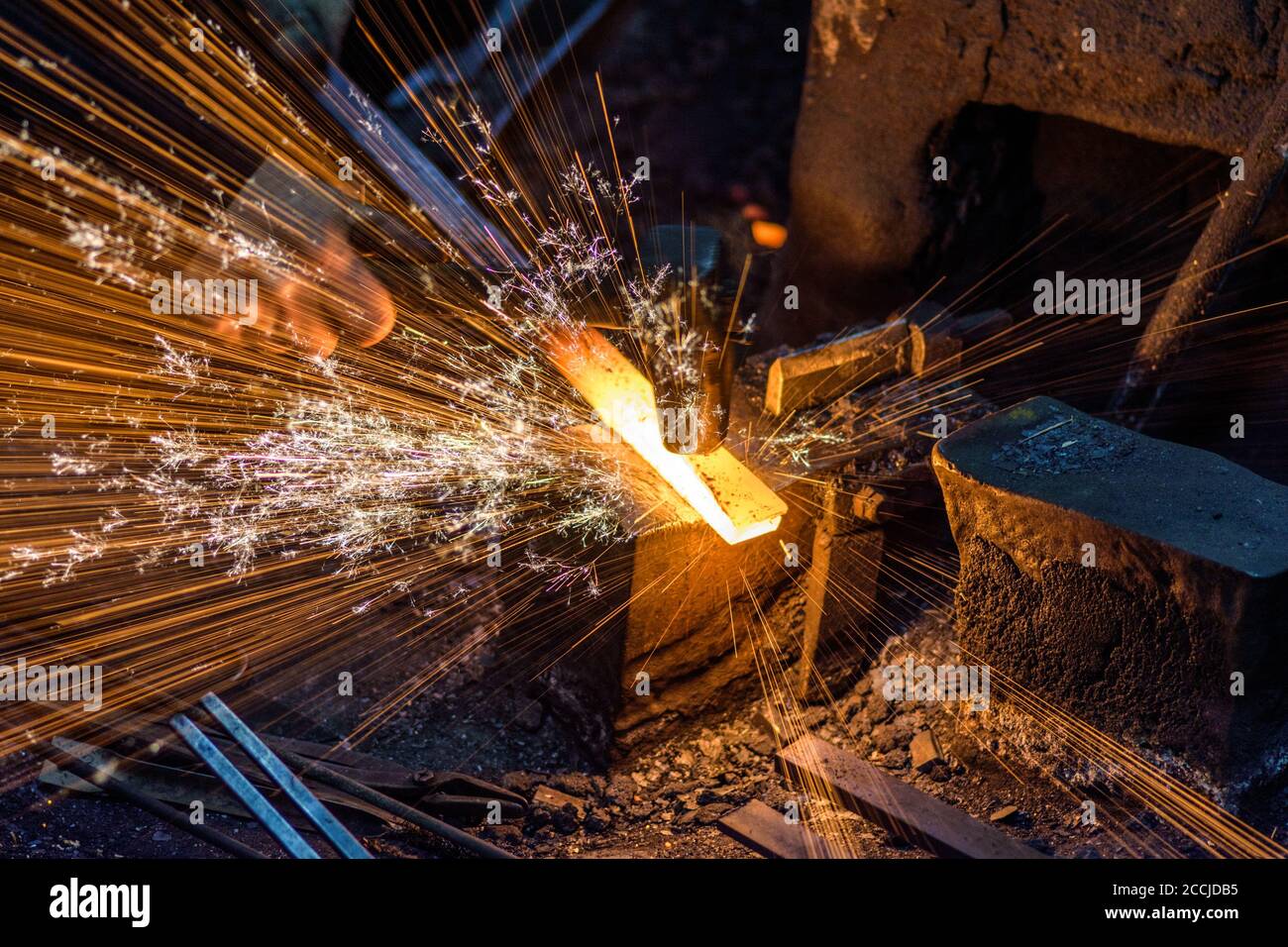 Blacksmith manually the molten metal on the anvil with spark