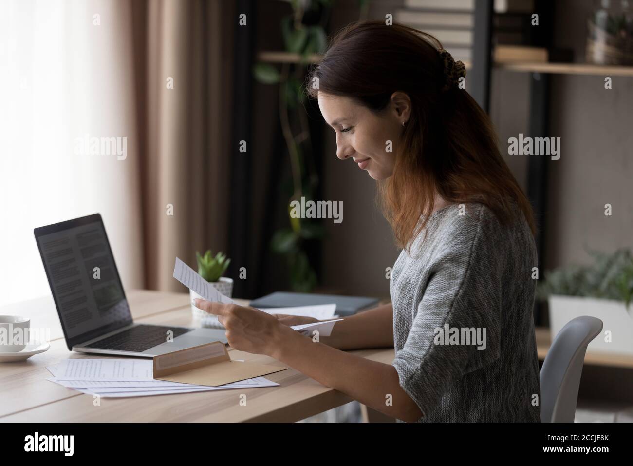Smiling young woman read paper letter correspondence Stock Photo