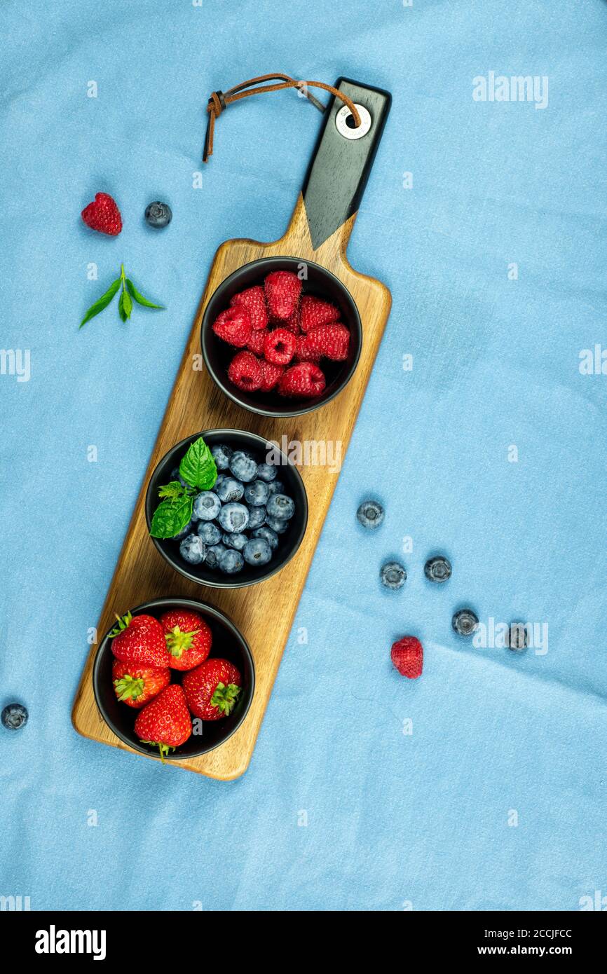 Selection of fruit strawberries blueberries and raspberries on a food plater and bowl showing healthy food choices Stock Photo